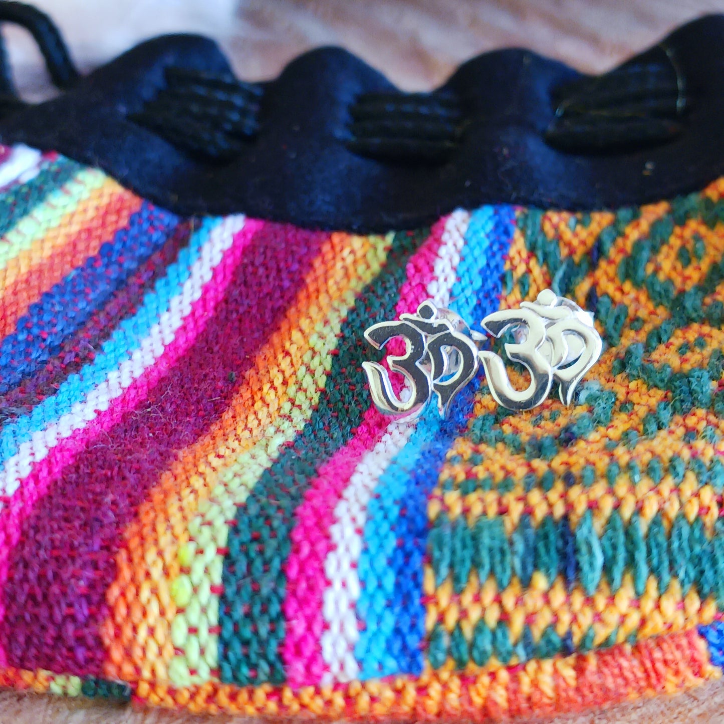 Om, a sacred mantra intoned at the beginning and end of prayers or used in meditation practices, is depicted in script in these stud earrings.