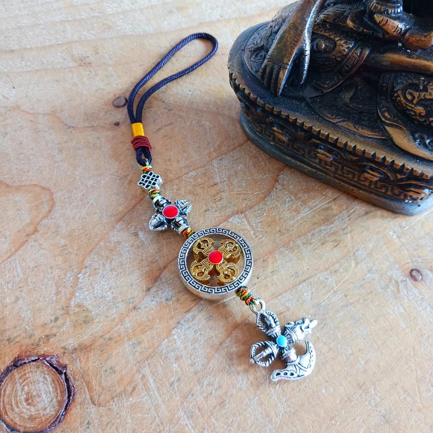 Bring the power of ancient Tibetan symbolism into your daily life with this handcrafted Buddhist protective pendant. Featuring the Double Dorje, a symbol of unwavering stability and protection from fear, and the Kartika, a ritual blade representing the cutting away of ignorance and attachment, this versatile charm can be hung in your car, placed in your home, or attached to your bag or key ring