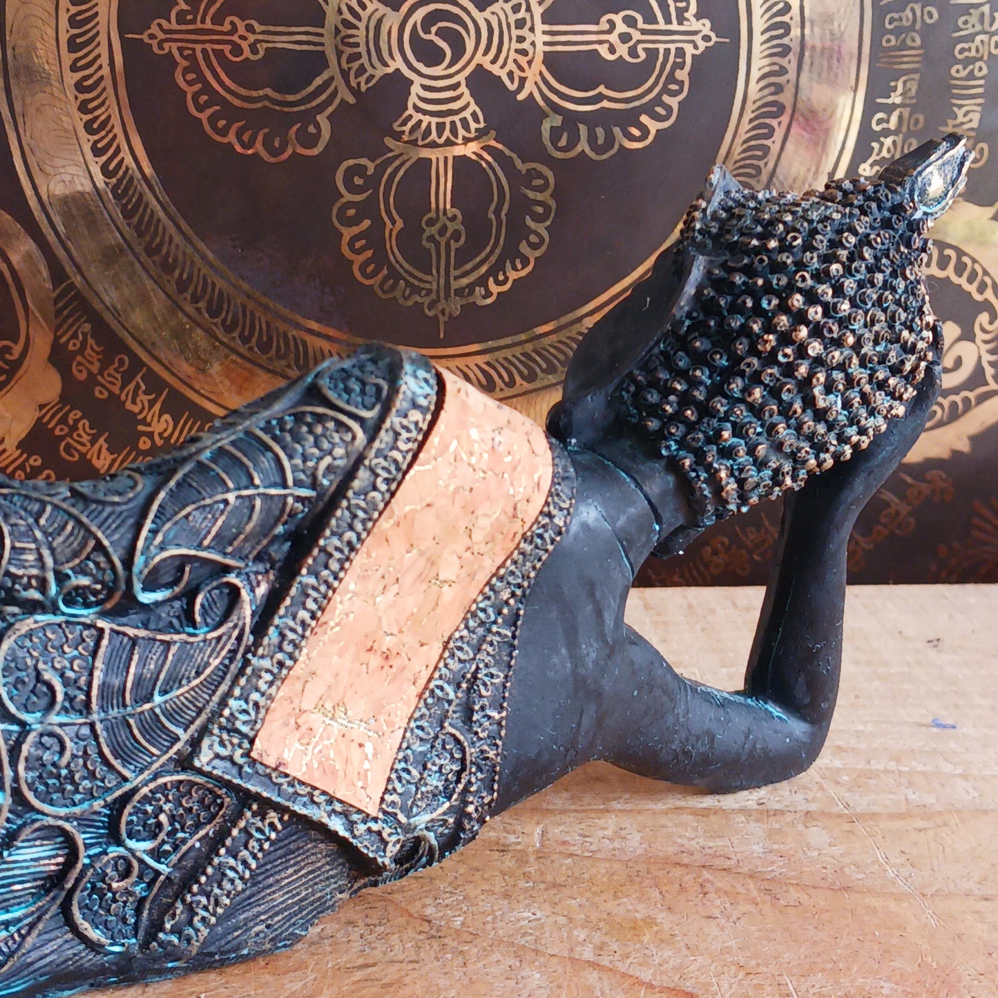 The statue features the Buddha in a graceful reclining pose, symbolizing his entry into nirvana. His left arm rests peacefully by his side, while his right hand cradles his head in a gesture of repose. The robe is intricately adorned with bodhi leaf motifs—sacred symbols of enlightenment and spiritual awakening.