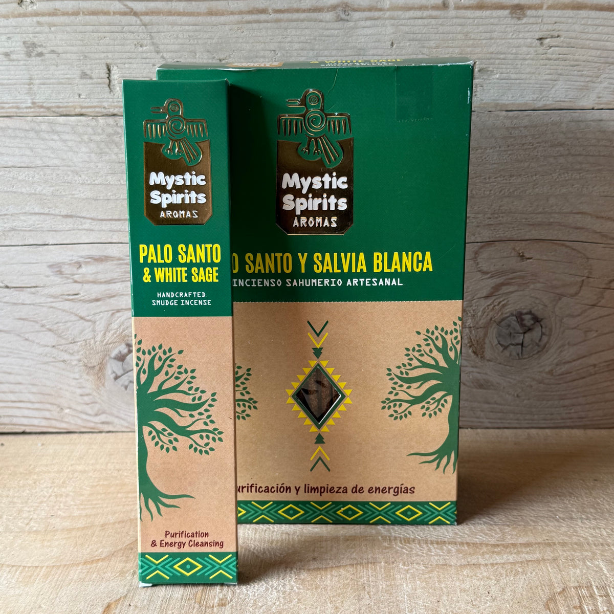 Two boxes of Mystic Spirits Aromas Palo Santo & White Sage incense sticks standing upright against a light wood plank background.