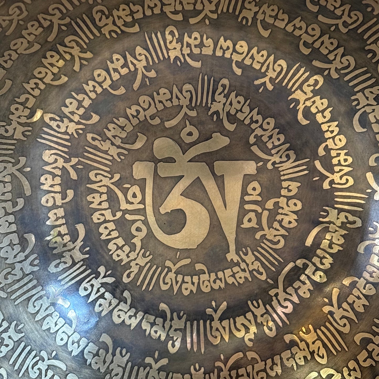 Decorative metal plate with intricate text and symbols, featuring a prominent 'Om' symbol.