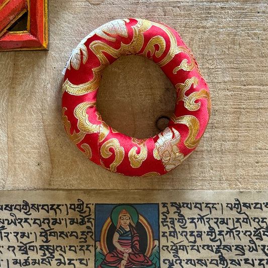 Cradle your singing bowl in divine comfort with our 11cm Doughnut Singing Bowl Cushion. As a practitioner of sound healing, I understand how every detail matters in sacred practice—including how your instruments rest when not in use.

This luxurious brocade ring isn't just a cushion; it's a ceremonial throne for your singing bowl. Designed to support smaller to medium-sized bowls, its doughnut shape stabilizes your bowl gently, allowing it to radiate its pure tones without interference. Whether you're medit