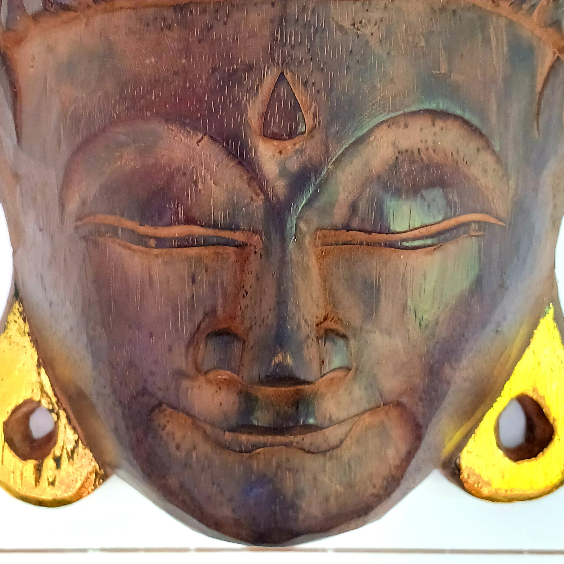 This skillfully crafted wall art of Lord Buddha with its beautiful, serene expression is both rustic and well-polished,  This mask has been hand carved from rain-tree wood by Indonesian artisans and is finished with gold leaf effect embellishment.&nbsp;  As this item is hand carved slight variations should be expected.  Size: Approx: 19cm × 28cm × 9cm Handmade and Fairtrade from Indonesia