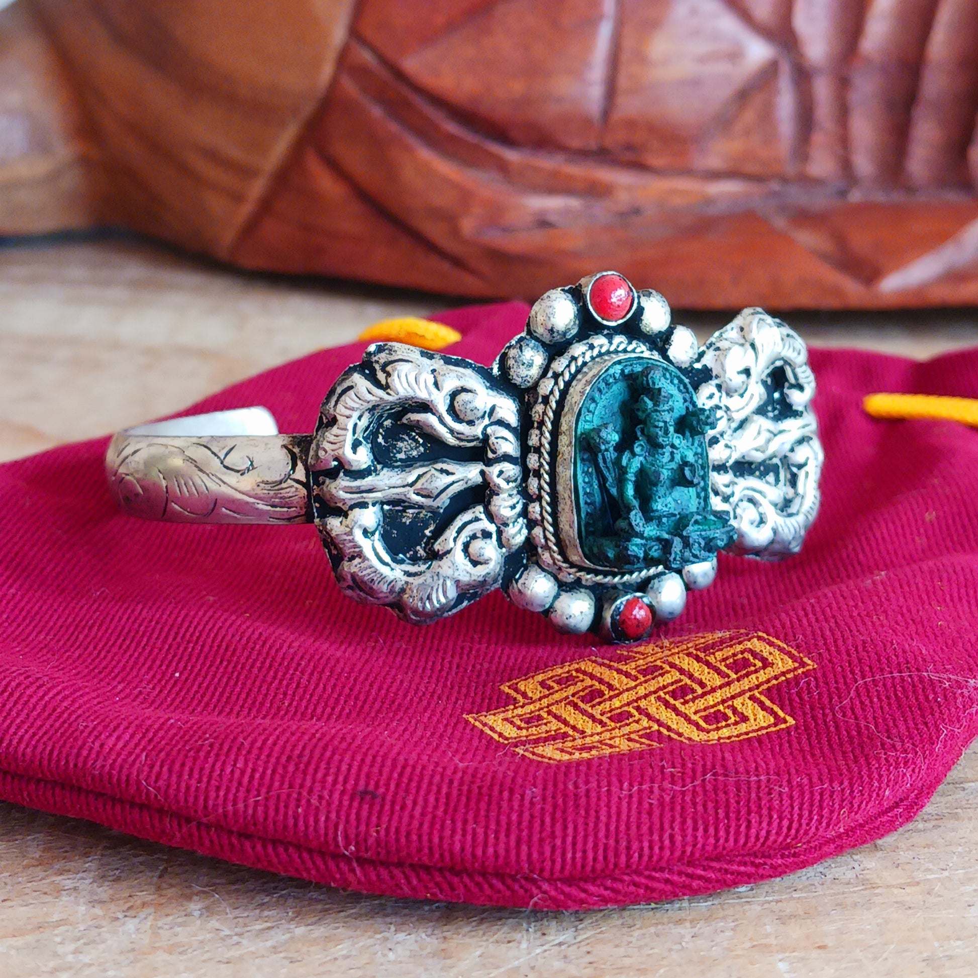 This handmade Tibetan bracelet has a turquoise Tibetan deity on the front. It has Vajra (Dorje) as a center piece.