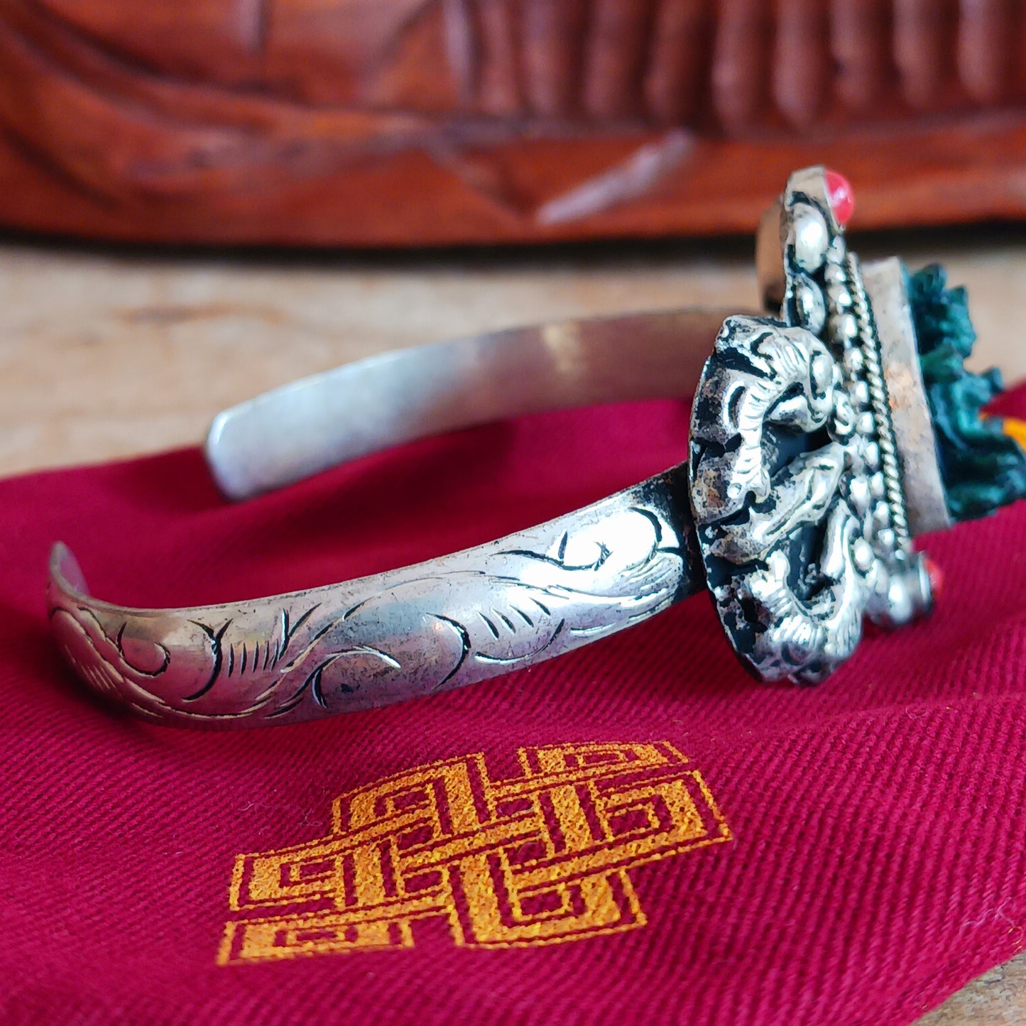 This handmade Tibetan bracelet has a turquoise Tibetan deity on the front. It has Vajra (Dorje) as a center piece.