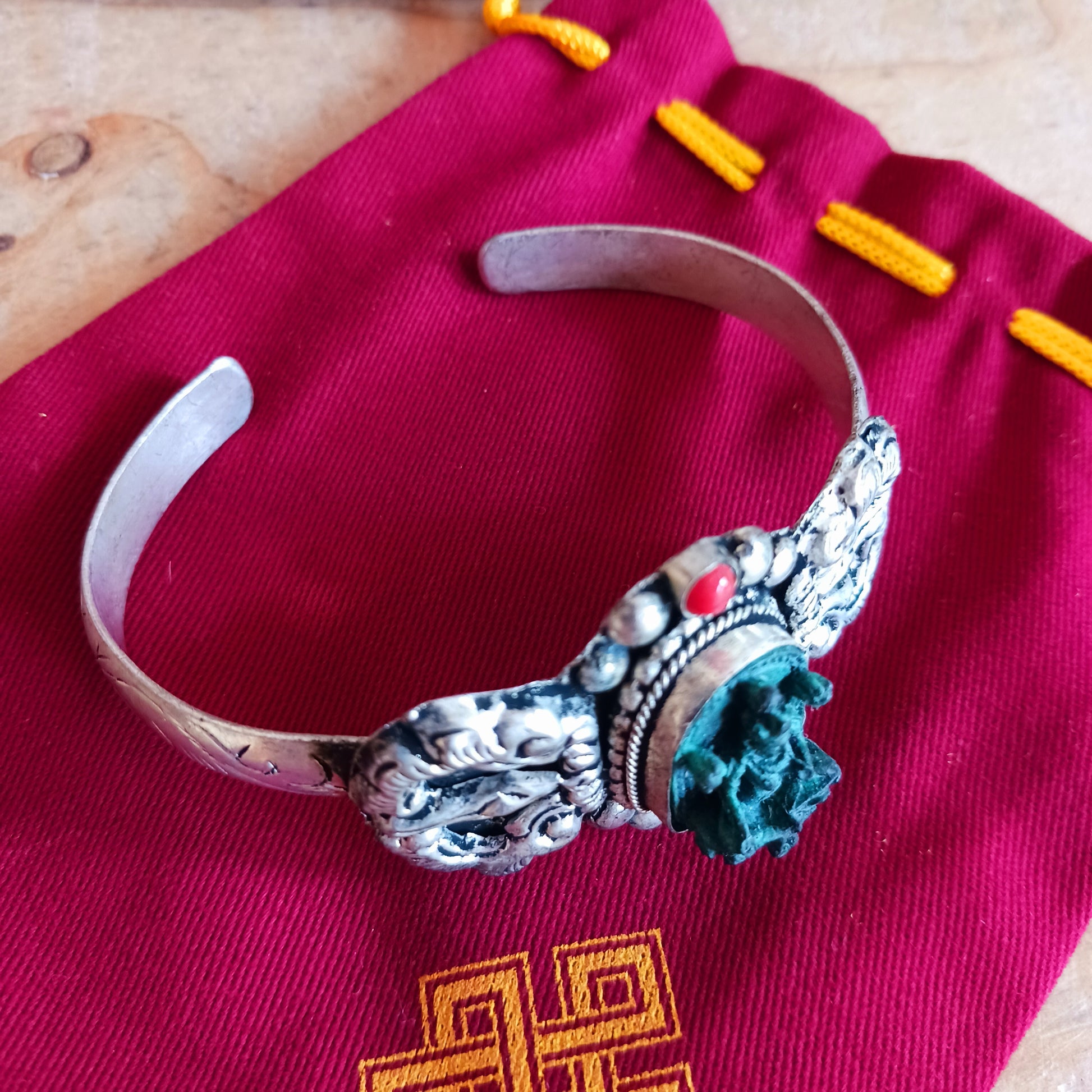 This handmade Tibetan bracelet has a turquoise Tibetan deity on the front. It has Vajra (Dorje) as a center piece.