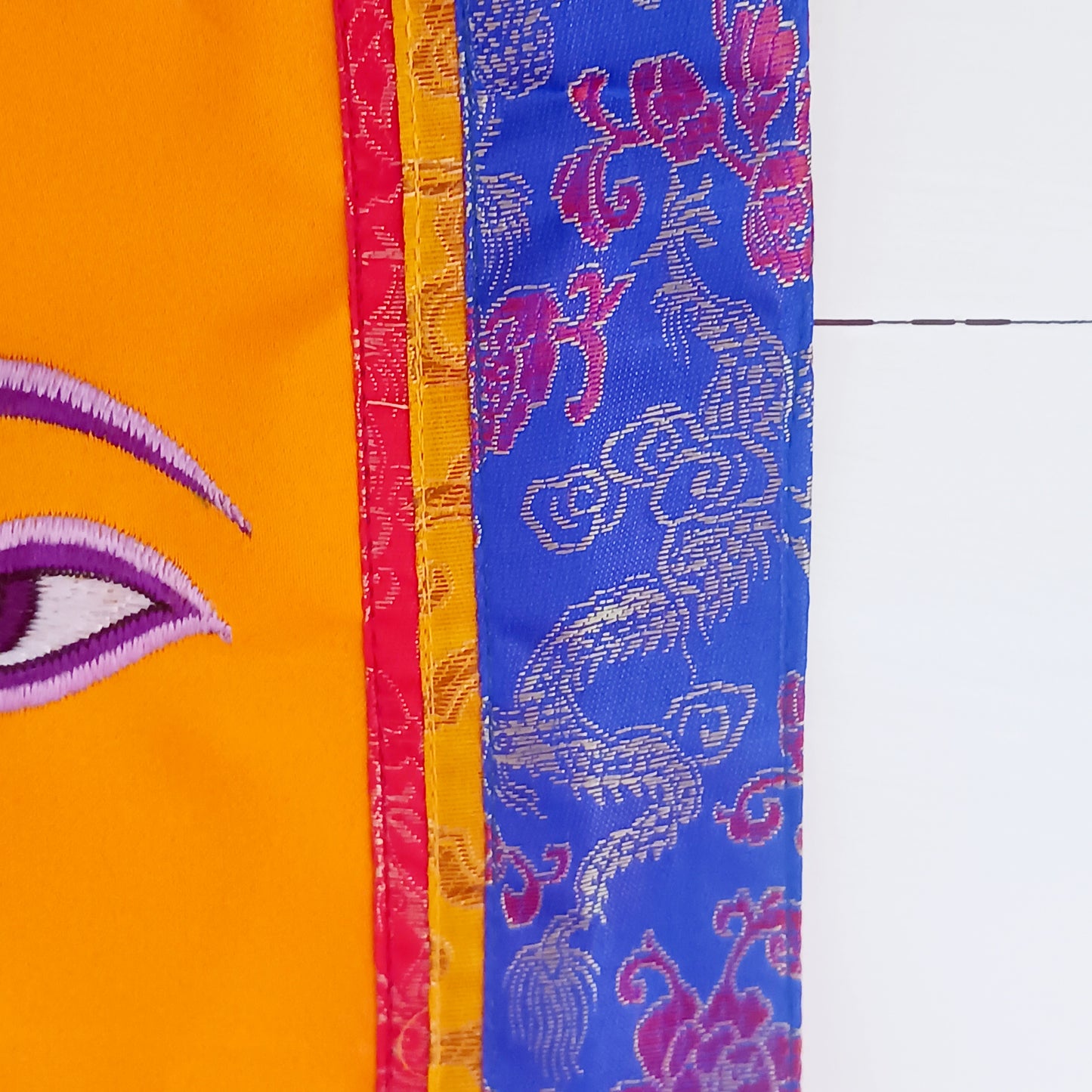 Representing an all-seeing, omniscient Buddha, these embroidered banners depict two eyes in the four cardinal directions, and the Nepali character for the number 1 sits between them like a question mark. This symbolizes the unity of all things and the one path to enlightenment.