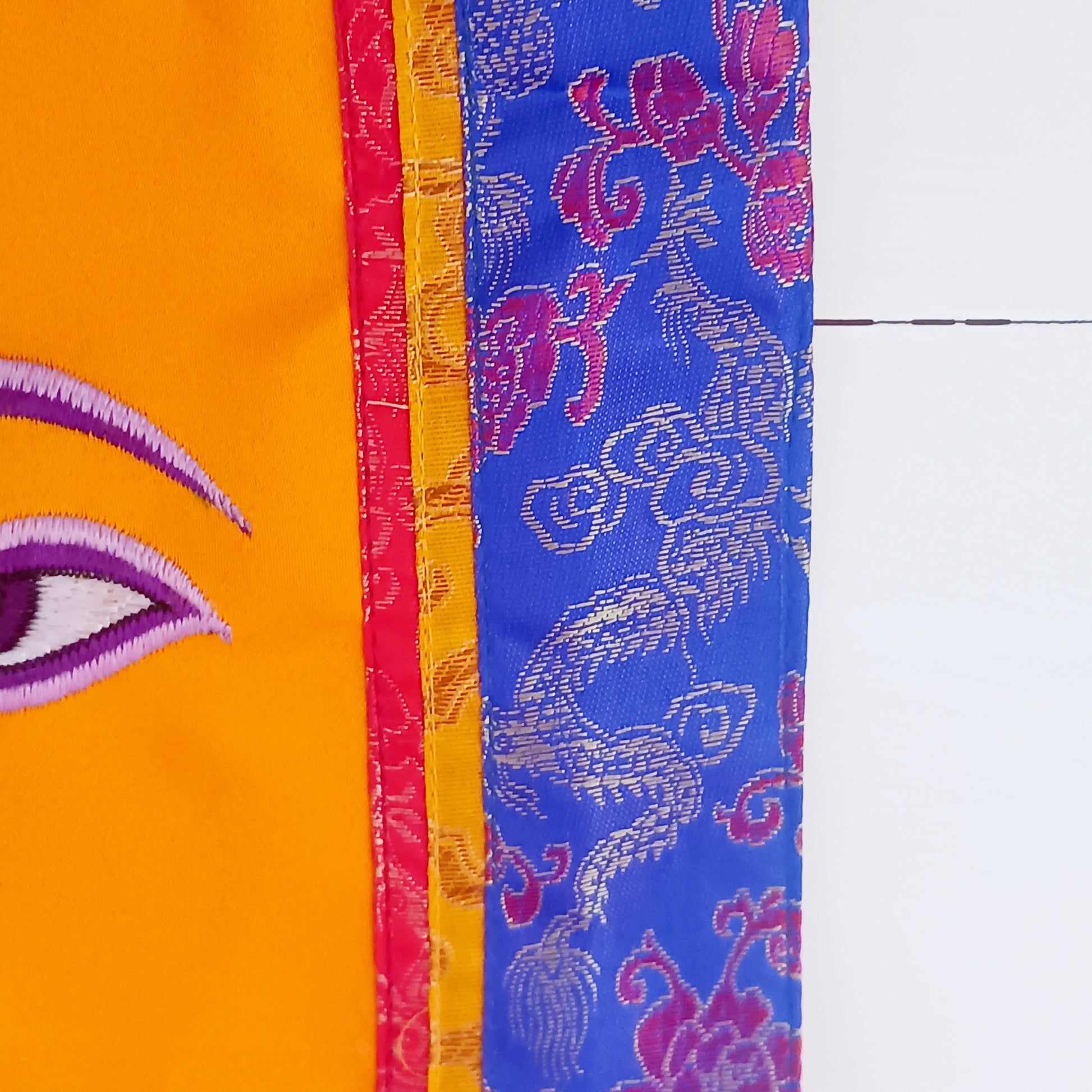 Representing an all-seeing, omniscient Buddha, these embroidered banners depict two eyes in the four cardinal directions, and the Nepali character for the number 1 sits between them like a question mark. This symbolizes the unity of all things and the one path to enlightenment.