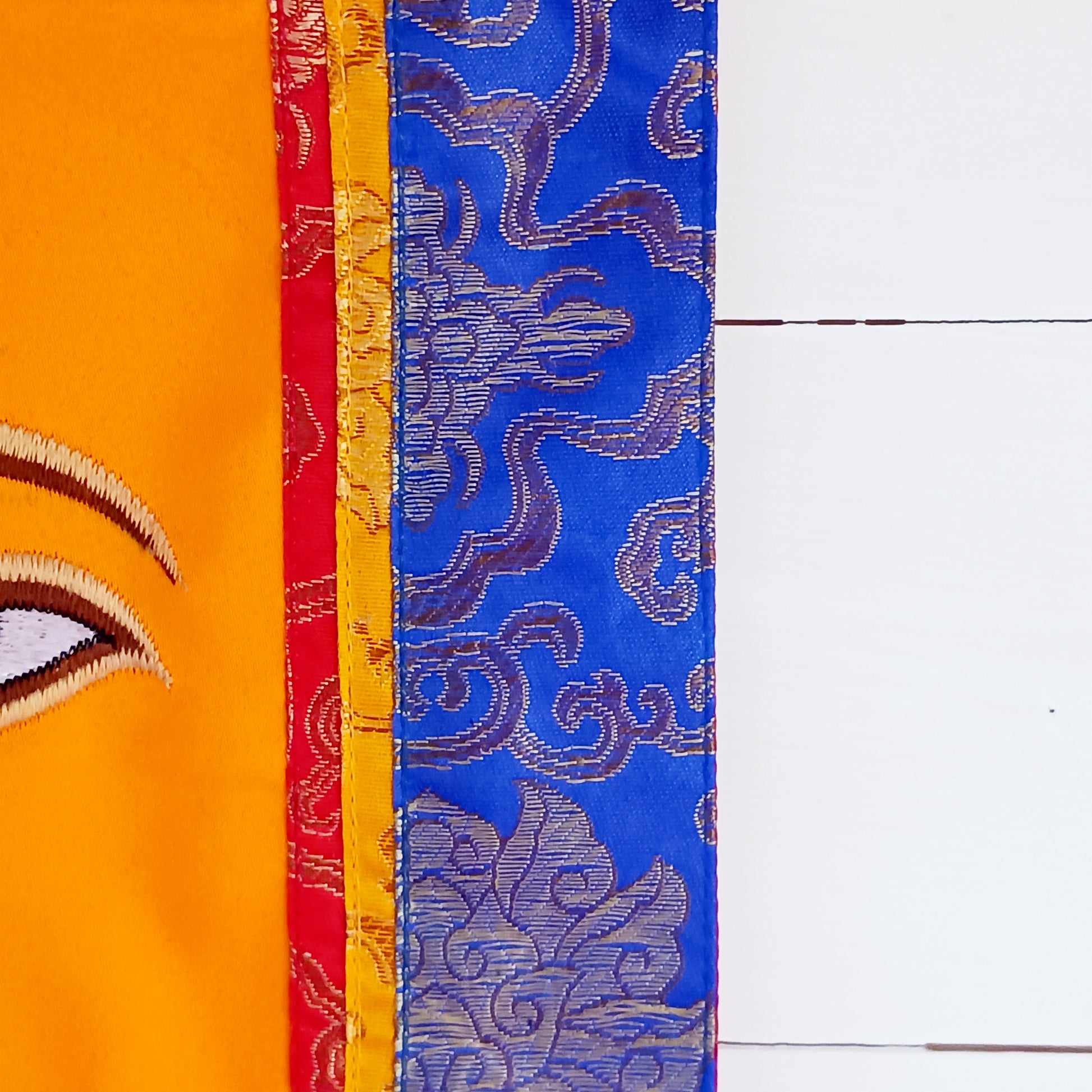 Representing an all-seeing, omniscient Buddha, these embroidered banners depict two eyes in the four cardinal directions, and the Nepali character for the number 1 sits between them like a question mark. This symbolizes the unity of all things and the one path to enlightenment.