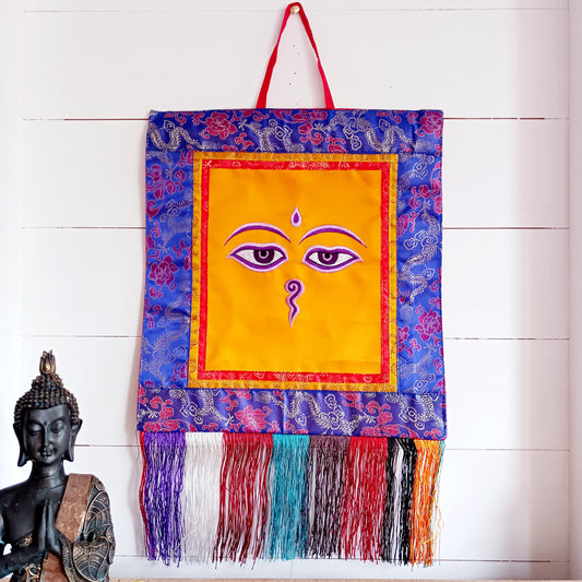 Representing an all-seeing, omniscient Buddha, these embroidered banners depict two eyes in the four cardinal directions, and the Nepali character for the number 1 sits between them like a question mark. This symbolizes the unity of all things and the one path to enlightenment.