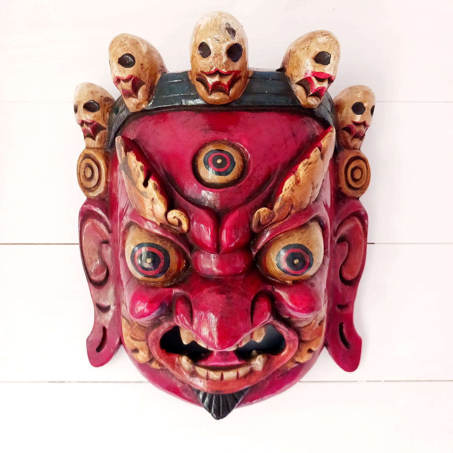 This Mahakala mask is a beautifully handcrafted wooden piece featuring intricate details and a unique design. Inspired by the powerful deity, this mask is a representation of strength, protection, and courage. Display it as a statement piece or use it in rituals for positive energy. 