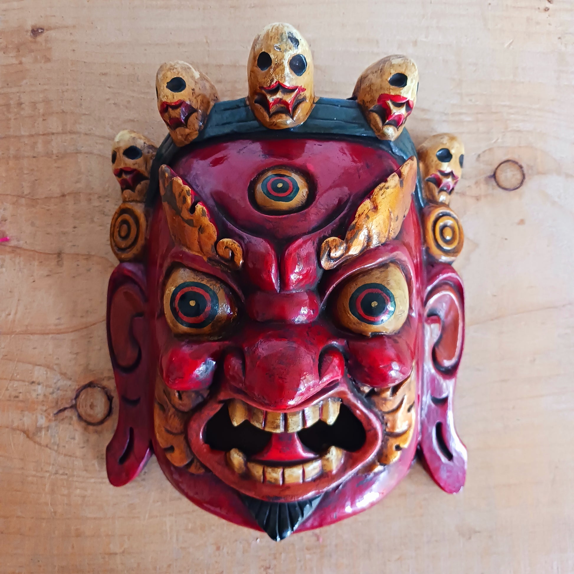 This Mahakala mask is a beautifully handcrafted wooden piece featuring intricate details and a unique design. Inspired by the powerful deity, this mask is a representation of strength, protection, and courage. Display it as a statement piece or use it in rituals for positive energy. 