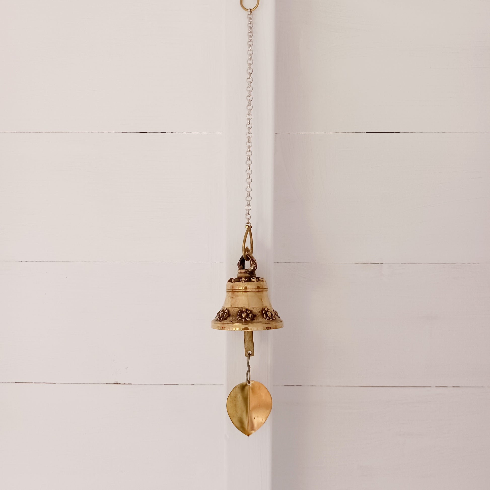 This hanging bell is made of brass in traditional Temple bell design, decorated with auspicious symbols and a brass bodhi leaf.