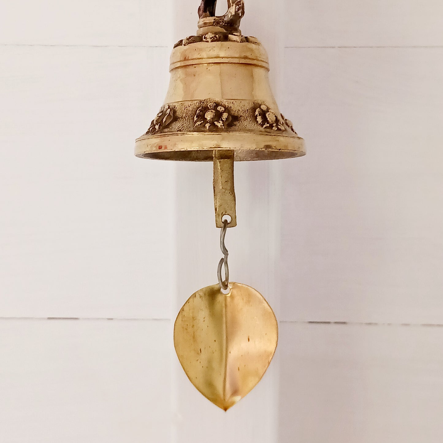 This hanging bell is made of brass in traditional Temple bell design, decorated with auspicious symbols and a brass bodhi leaf.