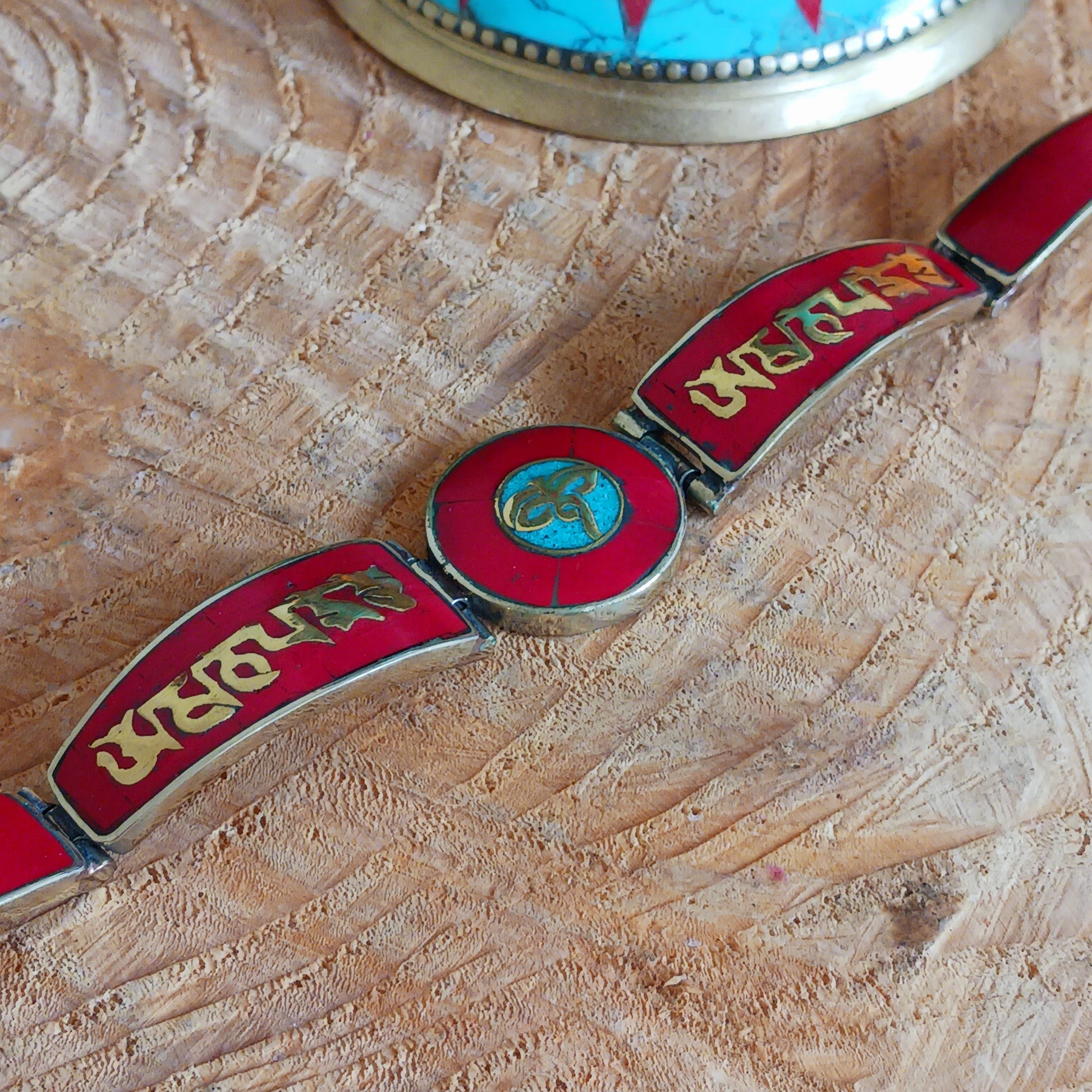 This Tibetan Mantra bracelet is made from brass with inlaid coral and turquoise chips.