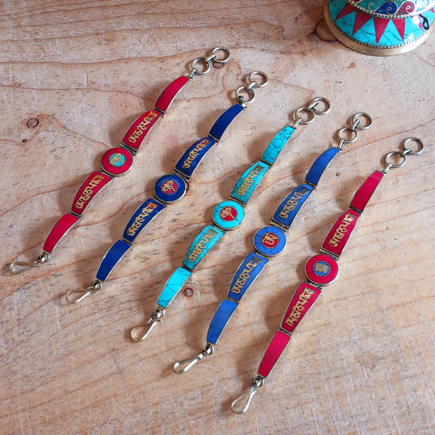 This Tibetan Mantra bracelets are made from brass with inlaid turquoise, lapis and coral chips.