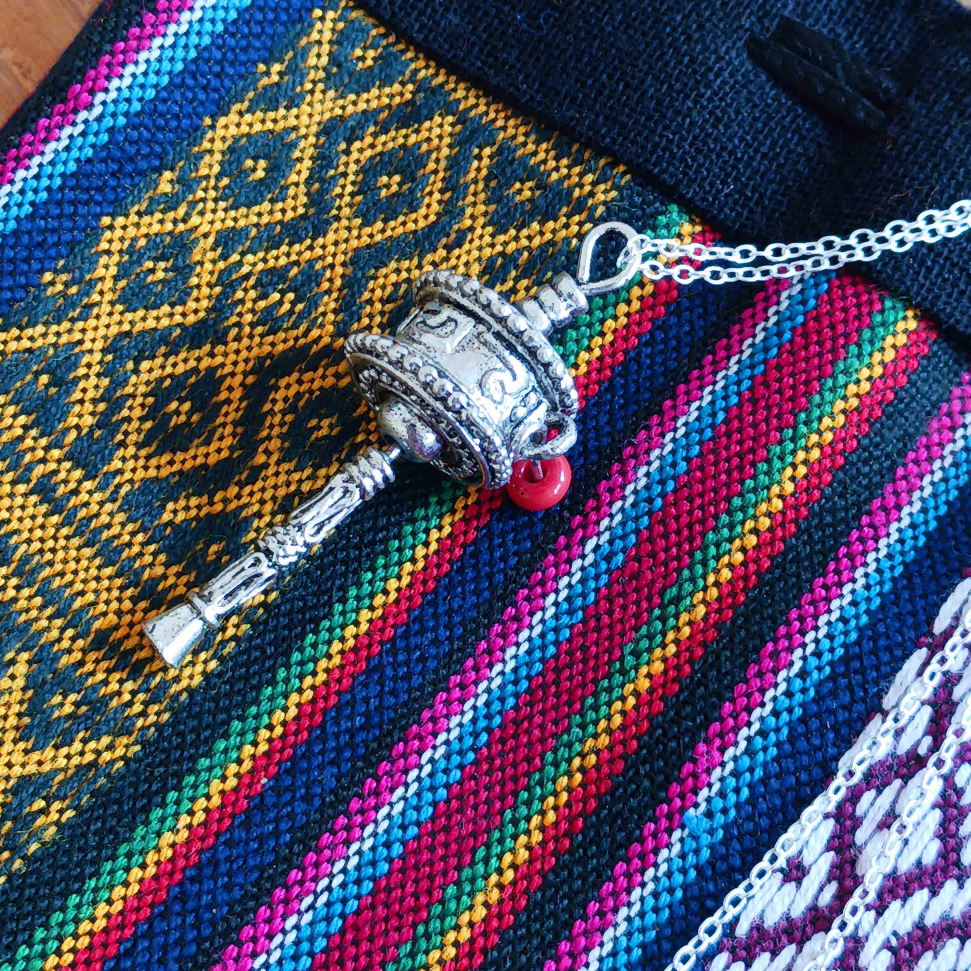 This sterling silver prayer wheel pendant has a Tibetan mantra engraved around the wheel.