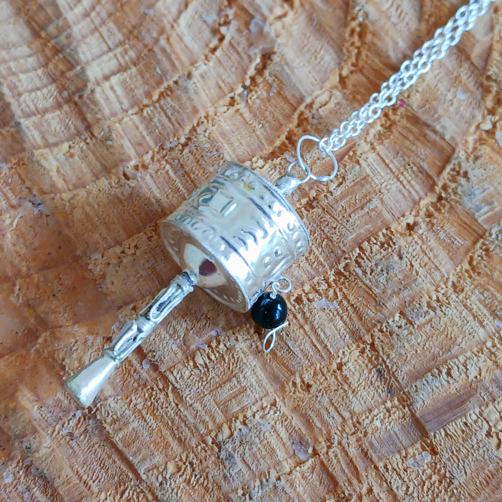 This Tibetan silver prayer wheel pendant has a Tibetan mantra engraved around the wheel.