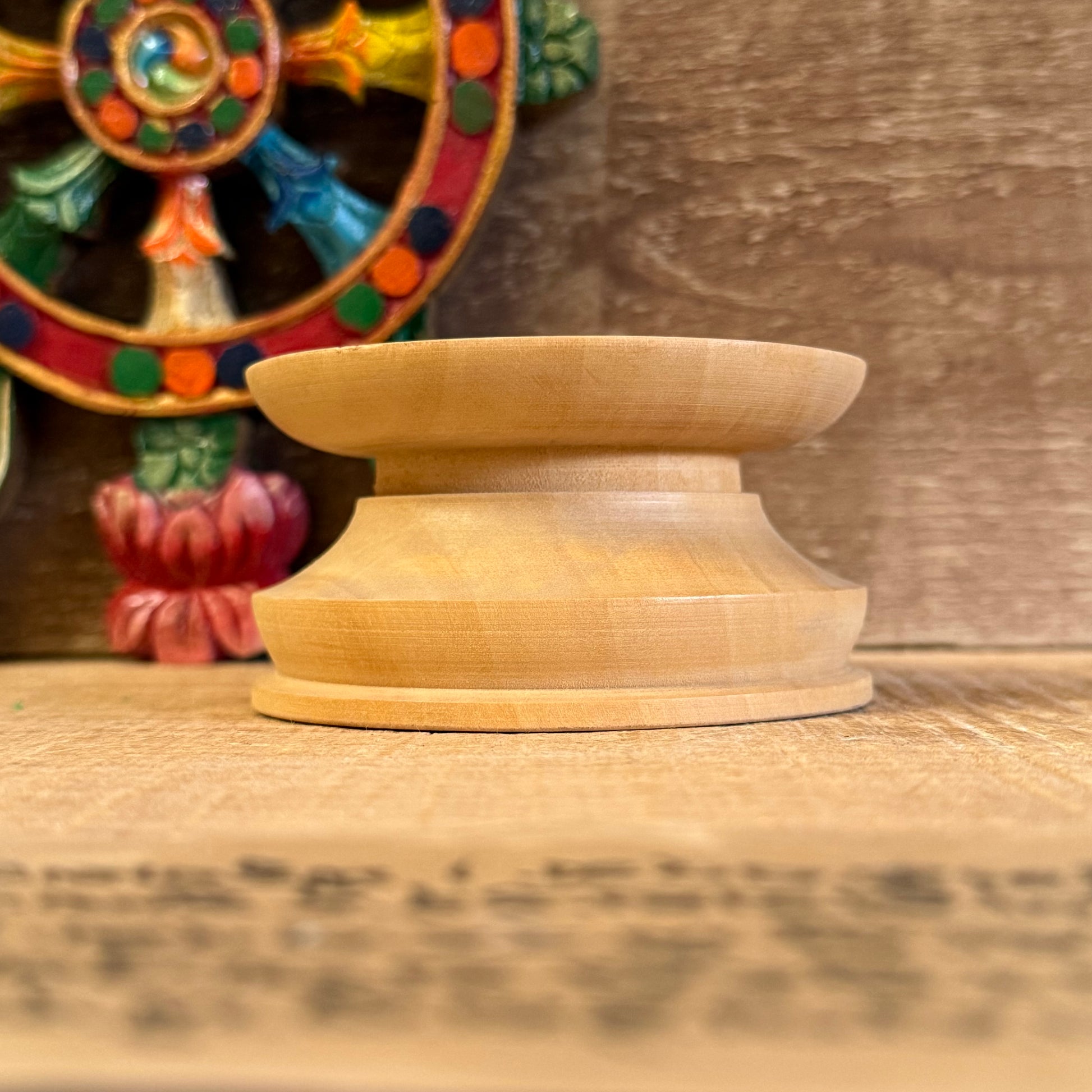 Let your singing bowl rest with dignity and balance on this simple yet elegant Singing Bowl Stand. Designed to support and display your sacred bowl without distraction, it brings harmony to any altar, meditation space, or shop setting.

Whether you're a practitioner, collector, or storekeeper, this understated stand highlights the beauty of your bowl while providing a stable and respectful base. Crafted in Nepal, it reflects the quiet care that accompanies traditional Buddhist practice.