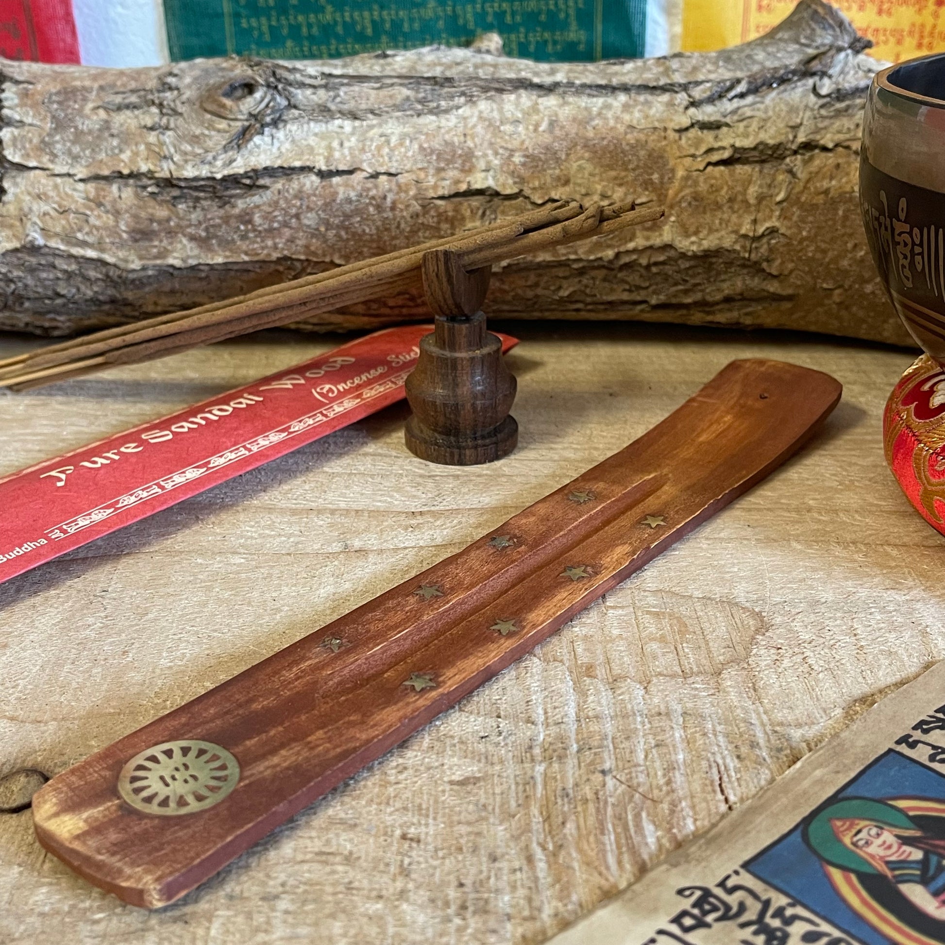 This wooden incense holder is designed as a simple, effective ash catcher with a classic, earthy aesthetic. Crafted from wood and adorned with brass inlays featuring a sun and stars motif, this design brings a touch of celestial charm to your incense rituals. The wooden body is slightly curved to hold incense sticks securely, while allowing ash to fall cleanly onto the base, keeping surfaces tidy.