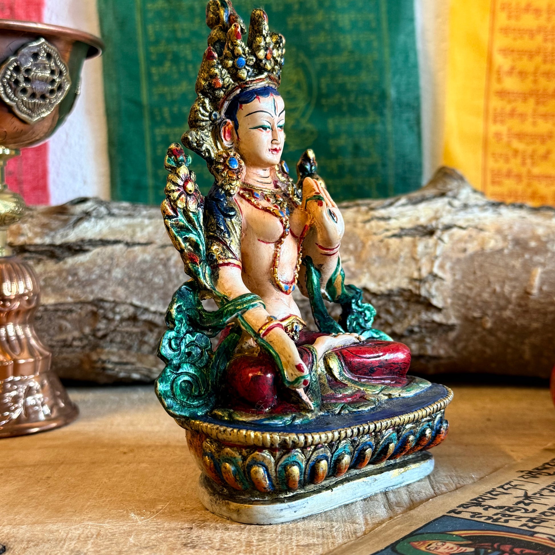 This is a beautifully intricate, handcrafted resin statue depicting White Tara, a revered goddess in Tibetan Buddhism. Known for her embodiment of compassion, healing, serenity, and longevity, she is a symbol of peace and enlightenment. The statue is skillfully painted and highlights White Tara's unique attributes: