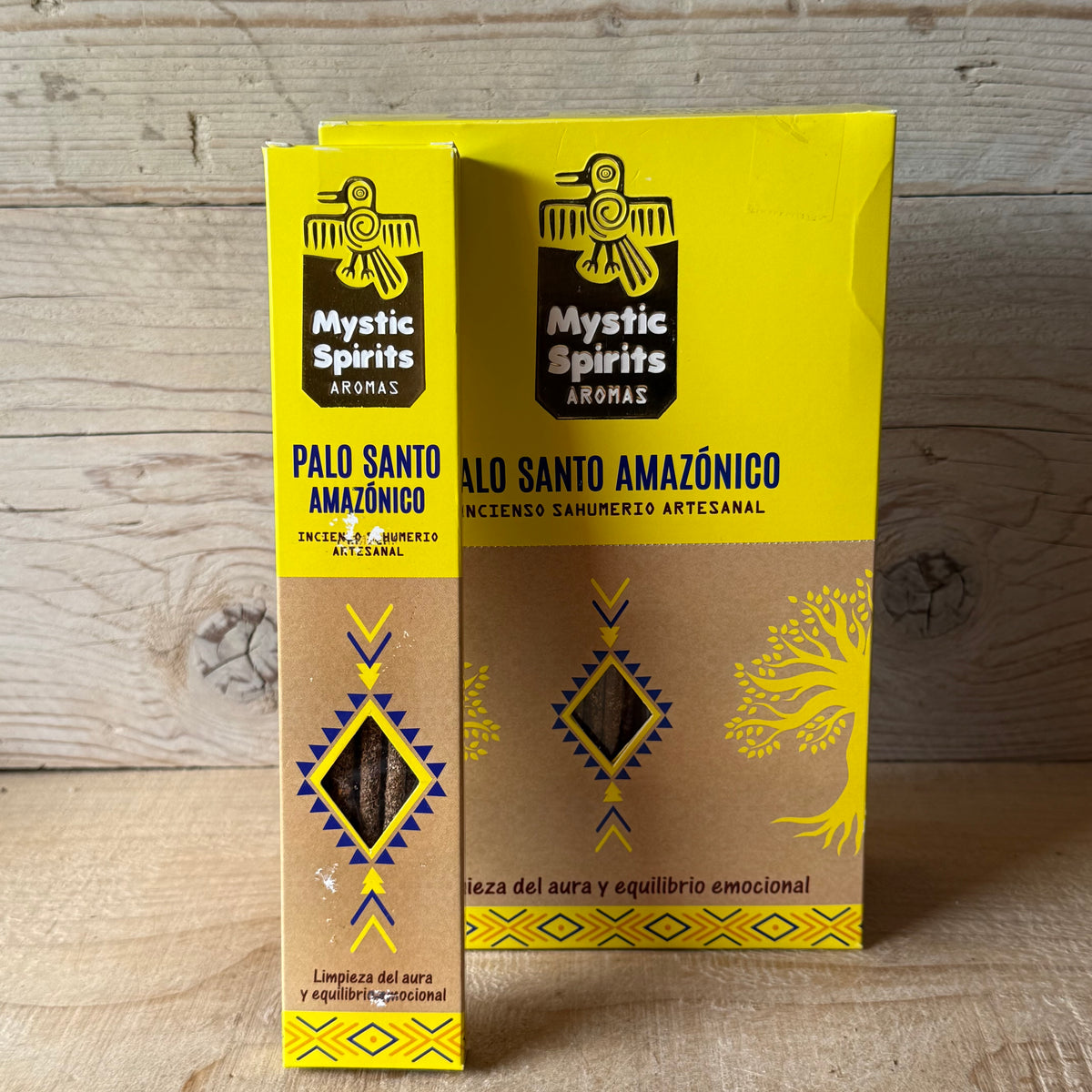 Two boxes of Mystic Spirits Aromas Palo Santo Amazonico incense sticks standing upright on a wooden surface against a light wood plank background.