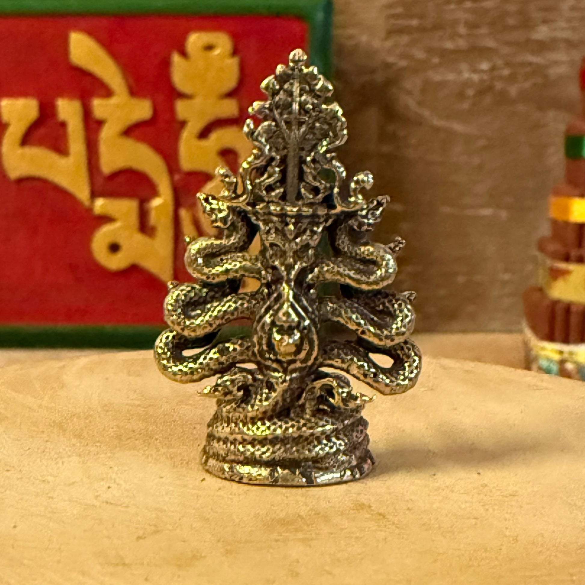 The Mini Brass Buddha with Nagas depicts a sacred moment in Buddhist tradition—when the naga king Mucalinda rose from the waters to shield the meditating Buddha from the storm. This timeless symbol represents divine protection, inner peace, and enlightenment.