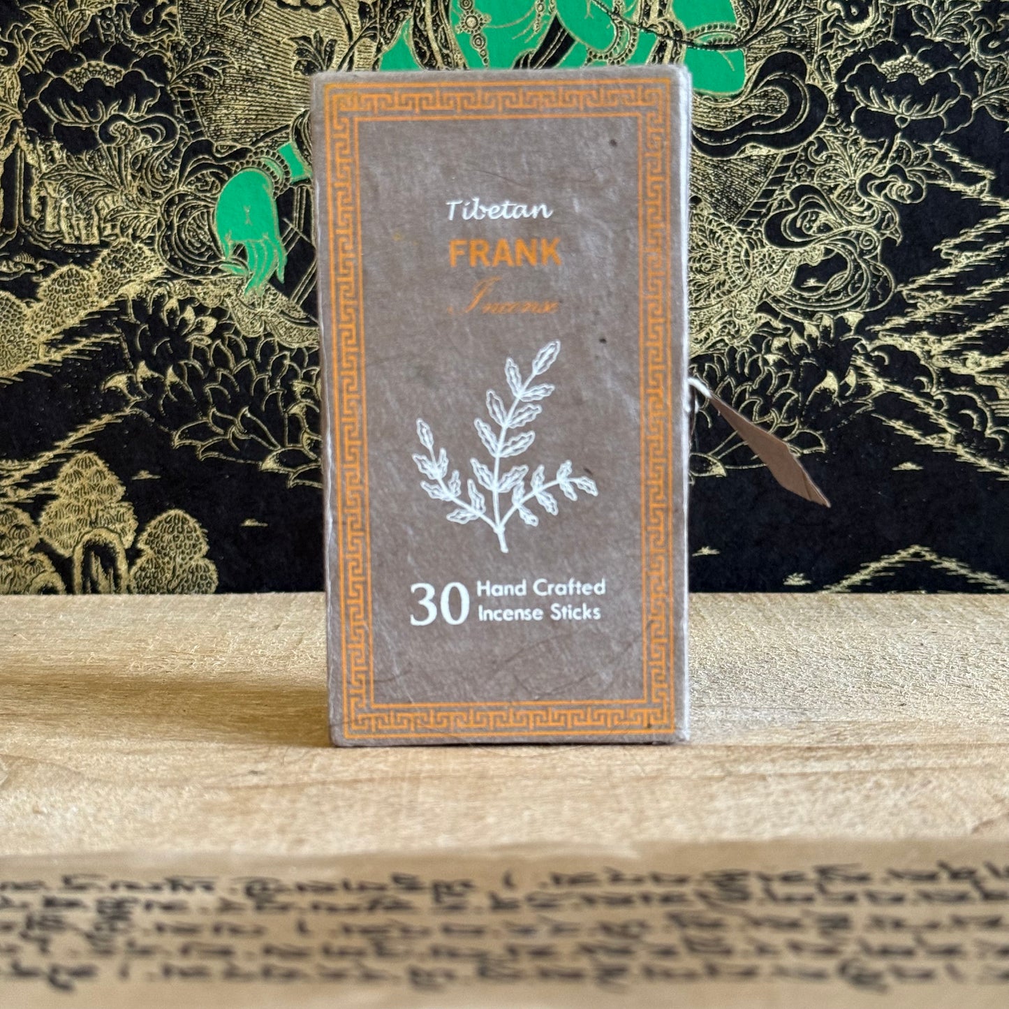 Tibetan Frankincense incense stick packaging on a wooden surface with decorative background