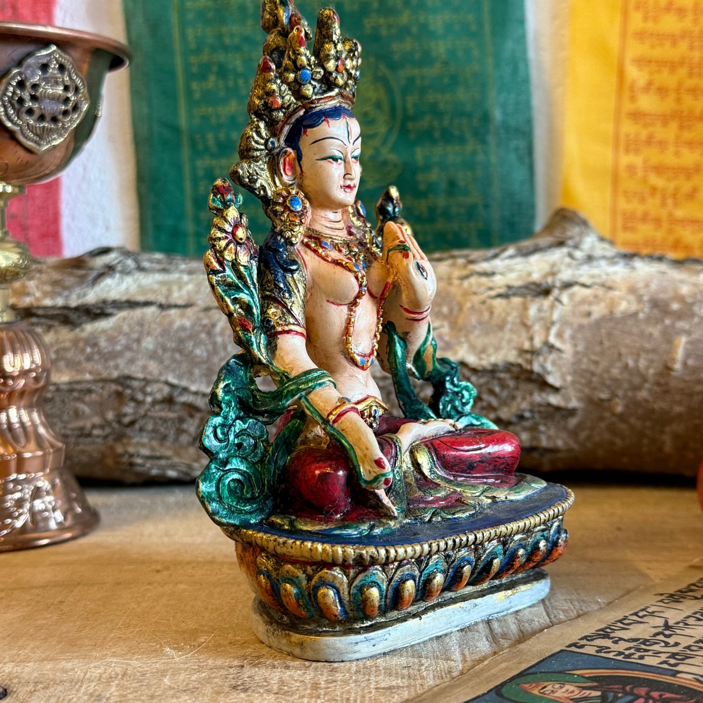 This is a beautifully intricate, handcrafted resin statue depicting White Tara, a revered goddess in Tibetan Buddhism. Known for her embodiment of compassion, healing, serenity, and longevity, she is a symbol of peace and enlightenment. The statue is skillfully painted and highlights White Tara's unique attributes: