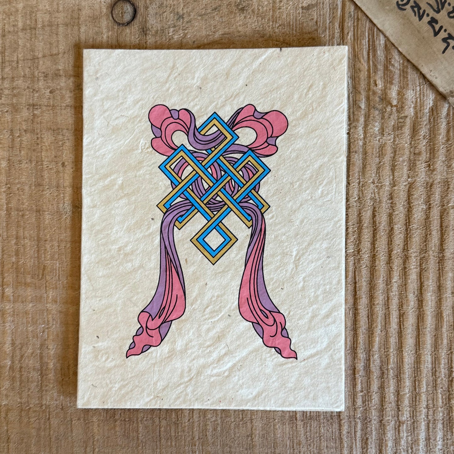 Beautifully coloured and decorated greetings card, made from Lokta paper, featuring the Endless Knot and Treasure Vase.

Lokta paper making is a traditional practice from the high altitude Himalayan forests of Nepal. The Lokta bush is a fast growing shrub and the paper making process helps to provide economic stability for some of Nepal's poorer rural people.

Size: approx. 15.5 x 11.5 cm

☸Buddhist design Lokta paper card with envelopes
☸Made from a sustainable plant source
☸Handmade and Fairtrade from Nep