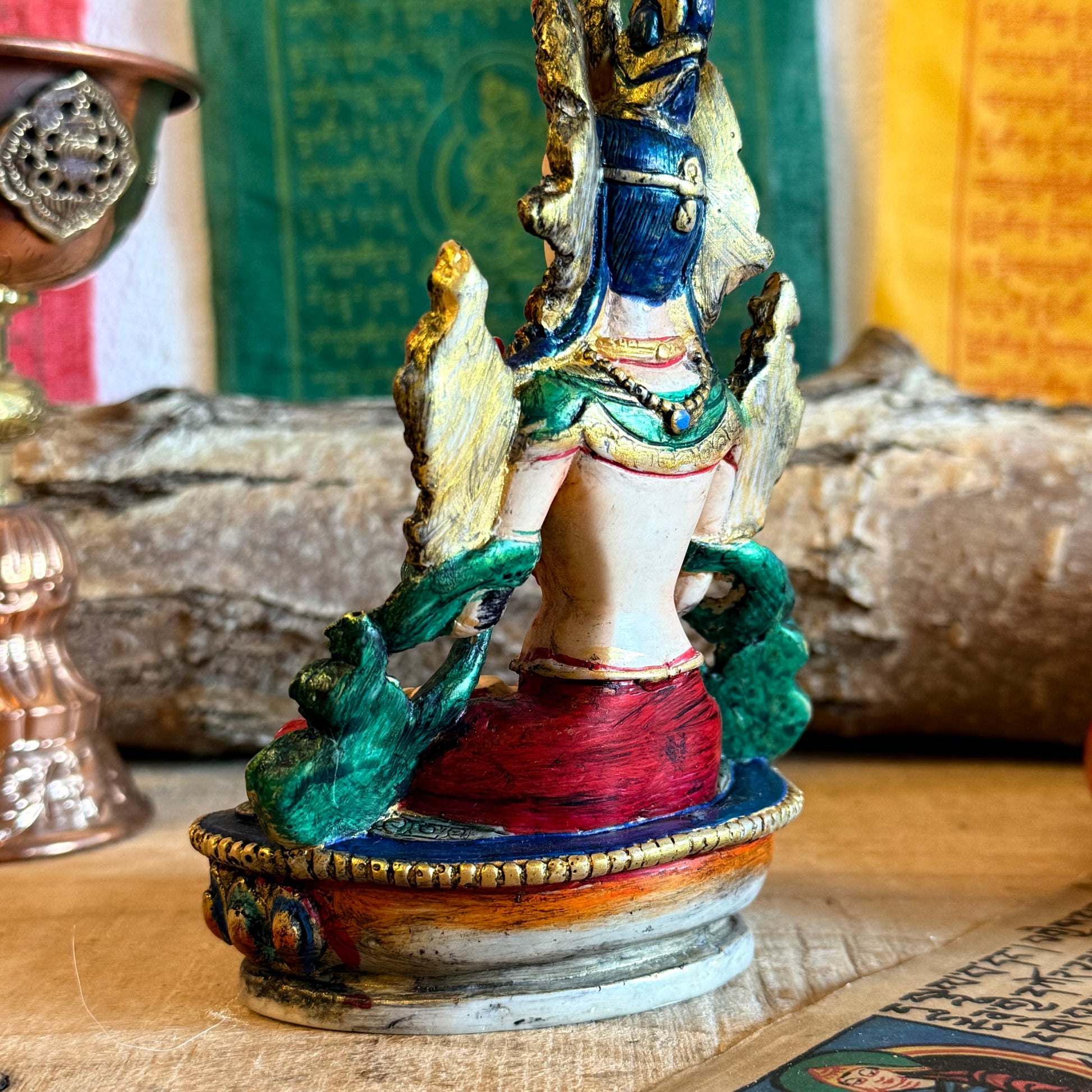 This is a beautifully intricate, handcrafted resin statue depicting White Tara, a revered goddess in Tibetan Buddhism. Known for her embodiment of compassion, healing, serenity, and longevity, she is a symbol of peace and enlightenment. The statue is skillfully painted and highlights White Tara's unique attributes: