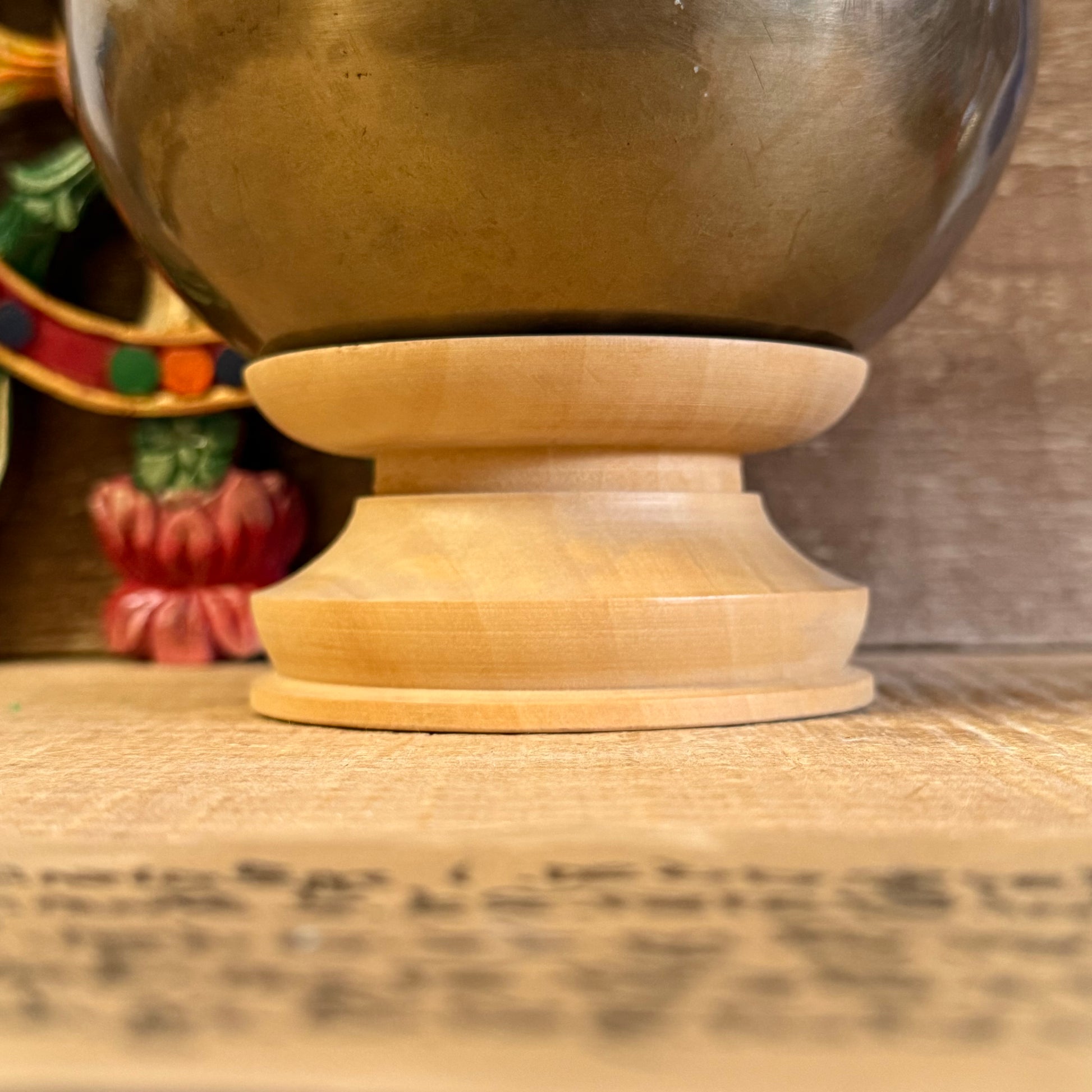 Let your singing bowl rest with dignity and balance on this simple yet elegant Singing Bowl Stand. Designed to support and display your sacred bowl without distraction, it brings harmony to any altar, meditation space, or shop setting.

Whether you're a practitioner, collector, or storekeeper, this understated stand highlights the beauty of your bowl while providing a stable and respectful base. Crafted in Nepal, it reflects the quiet care that accompanies traditional Buddhist practice.