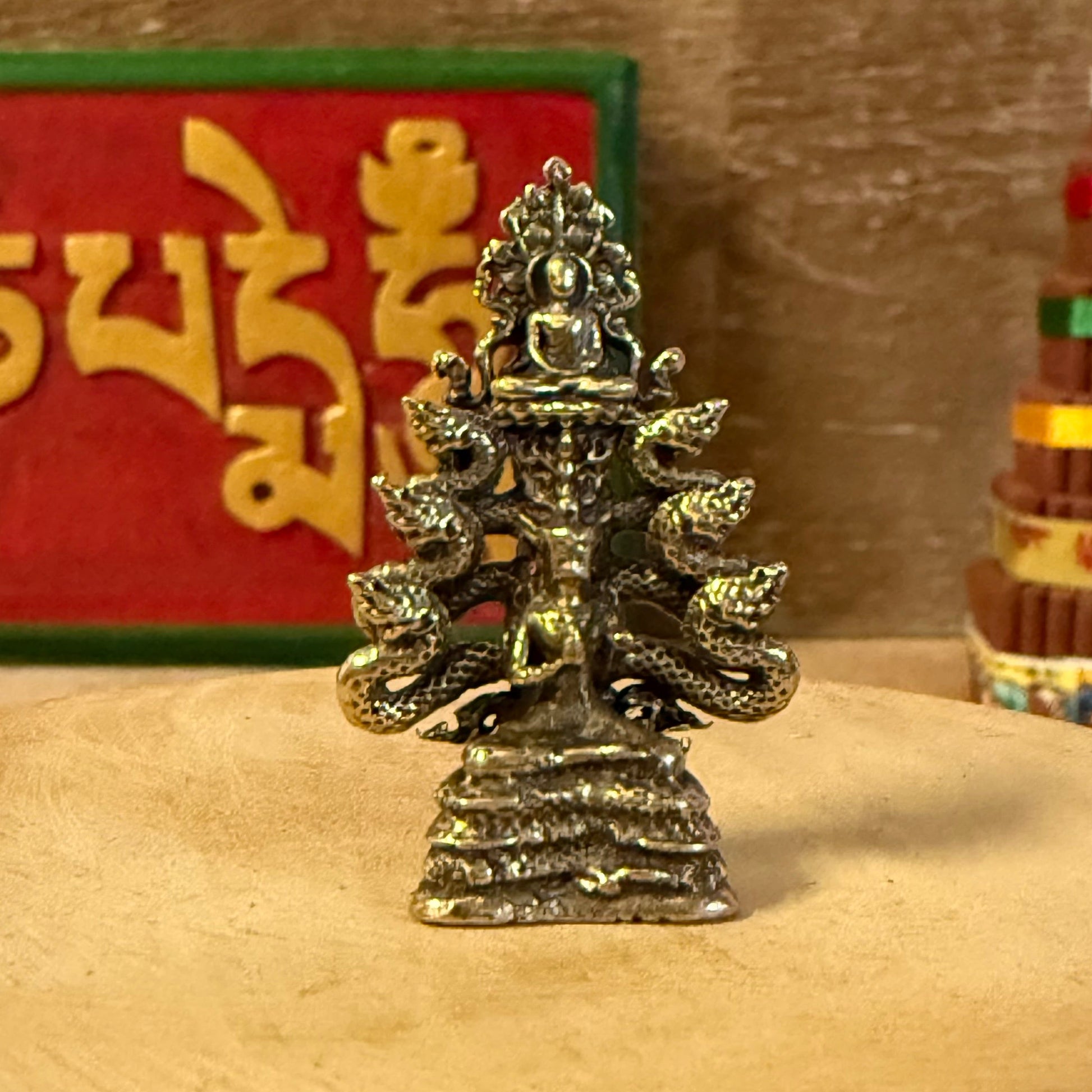 The Mini Brass Buddha with Nagas depicts a sacred moment in Buddhist tradition—when the naga king Mucalinda rose from the waters to shield the meditating Buddha from the storm. This timeless symbol represents divine protection, inner peace, and enlightenment.