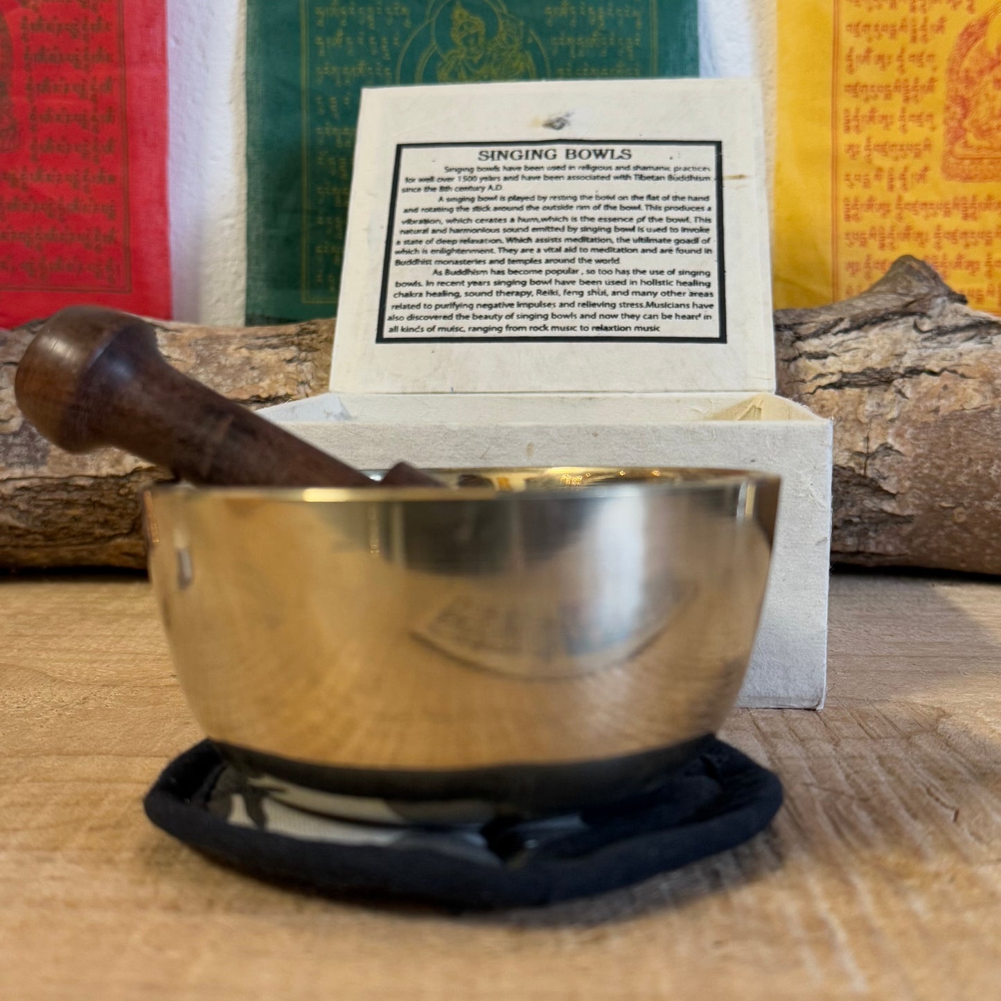 Singing bowl gift set and it contains a machine made brass singing bowl, a wooden striker and a simple cushion; all presented in an elegant handmade Himalayan Lokta paper box.