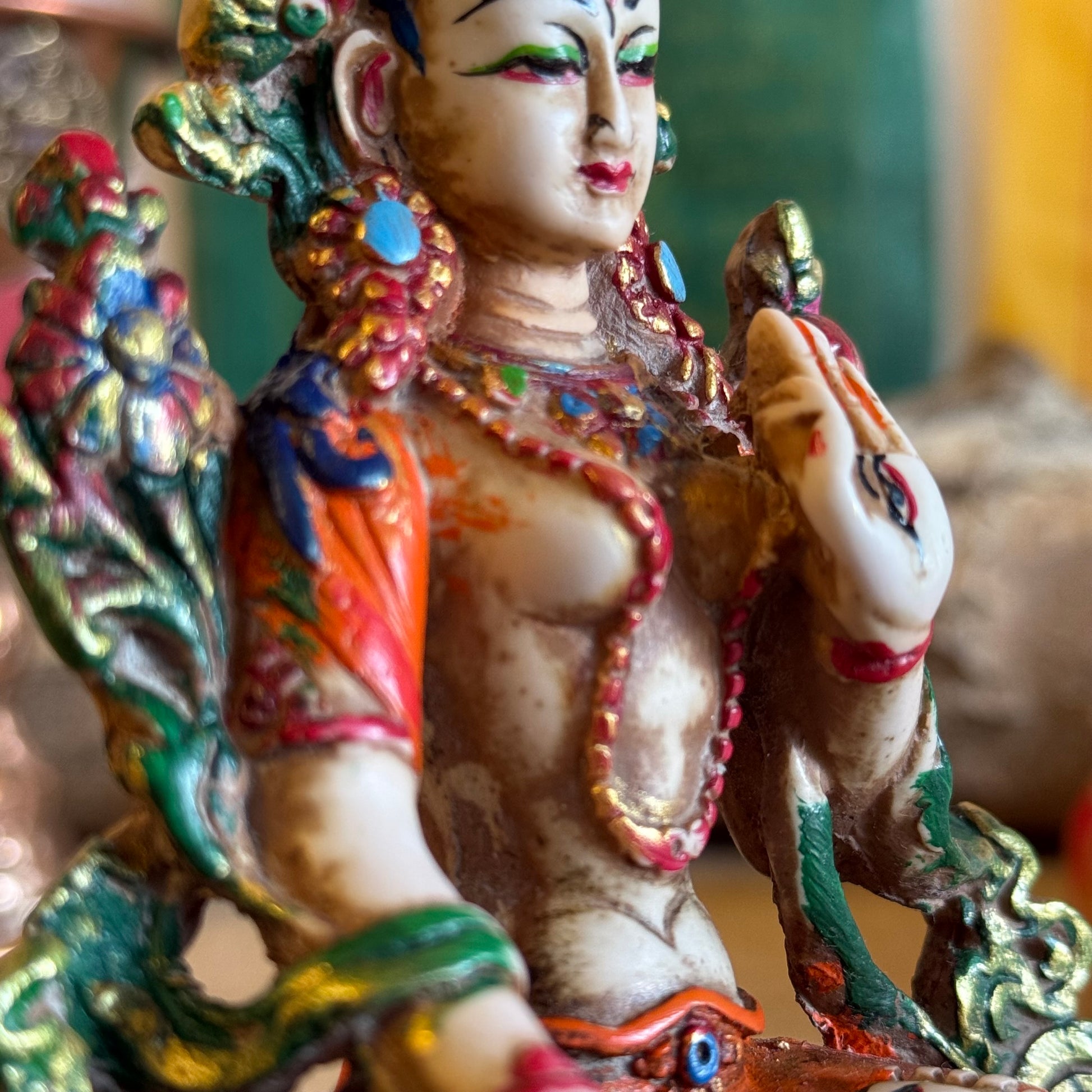 This is a beautifully intricate, handcrafted resin statue depicting White Tara, a revered goddess in Tibetan Buddhism. Known for her embodiment of compassion, healing, serenity, and longevity, she is a symbol of peace and enlightenment. The statue is skillfully painted and highlights White Tara's unique attributes:

Posture: She is seated in a tranquil, full lotus position, which signifies her meditative and composed nature, in contrast to Green Tara's more active pose with one foot extended.
Gesture: Her r