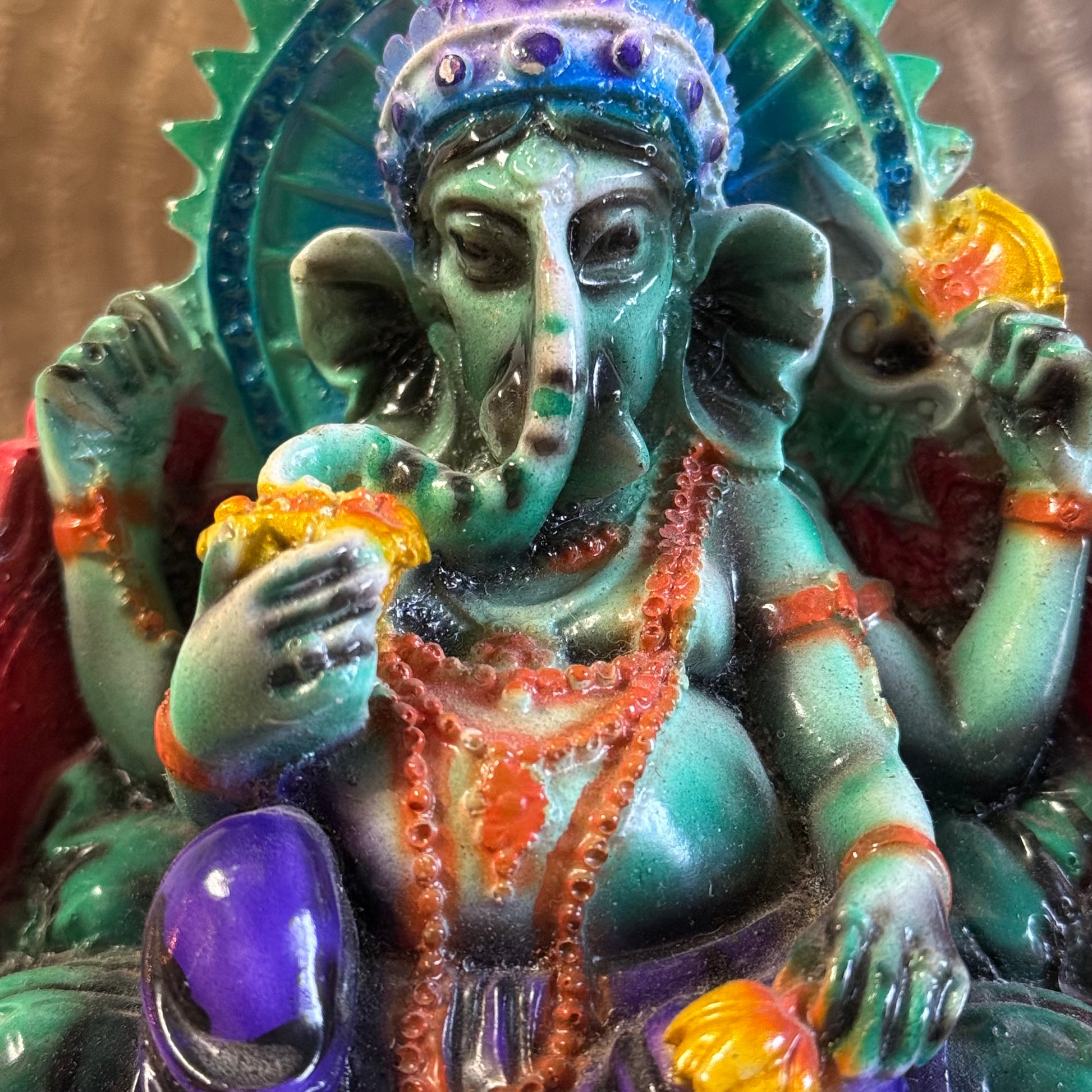 Hand-painted 15 cm resin Ganesh statue holding lotus, axe, and sweets.