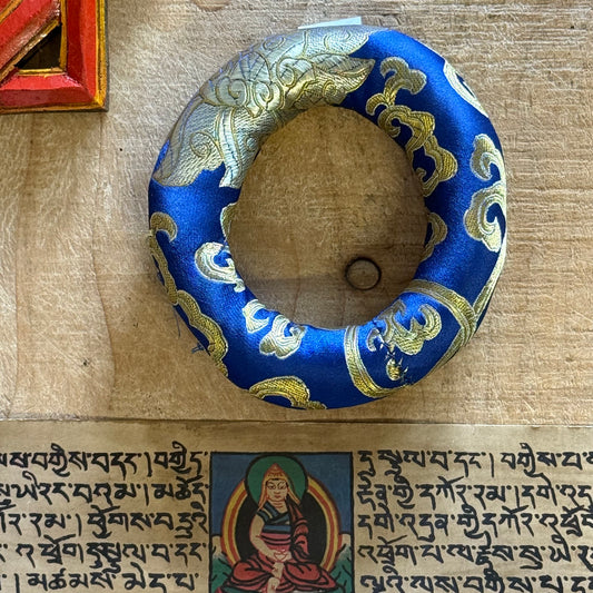 Cradle your singing bowl in divine comfort with our 11cm Doughnut Singing Bowl Cushion. As a practitioner of sound healing, I understand how every detail matters in sacred practice—including how your instruments rest when not in use.

This luxurious brocade ring isn't just a cushion; it's a ceremonial throne for your singing bowl. Designed to support smaller to medium-sized bowls, its doughnut shape stabilizes your bowl gently, allowing it to radiate its pure tones without interference. Whether you're medit