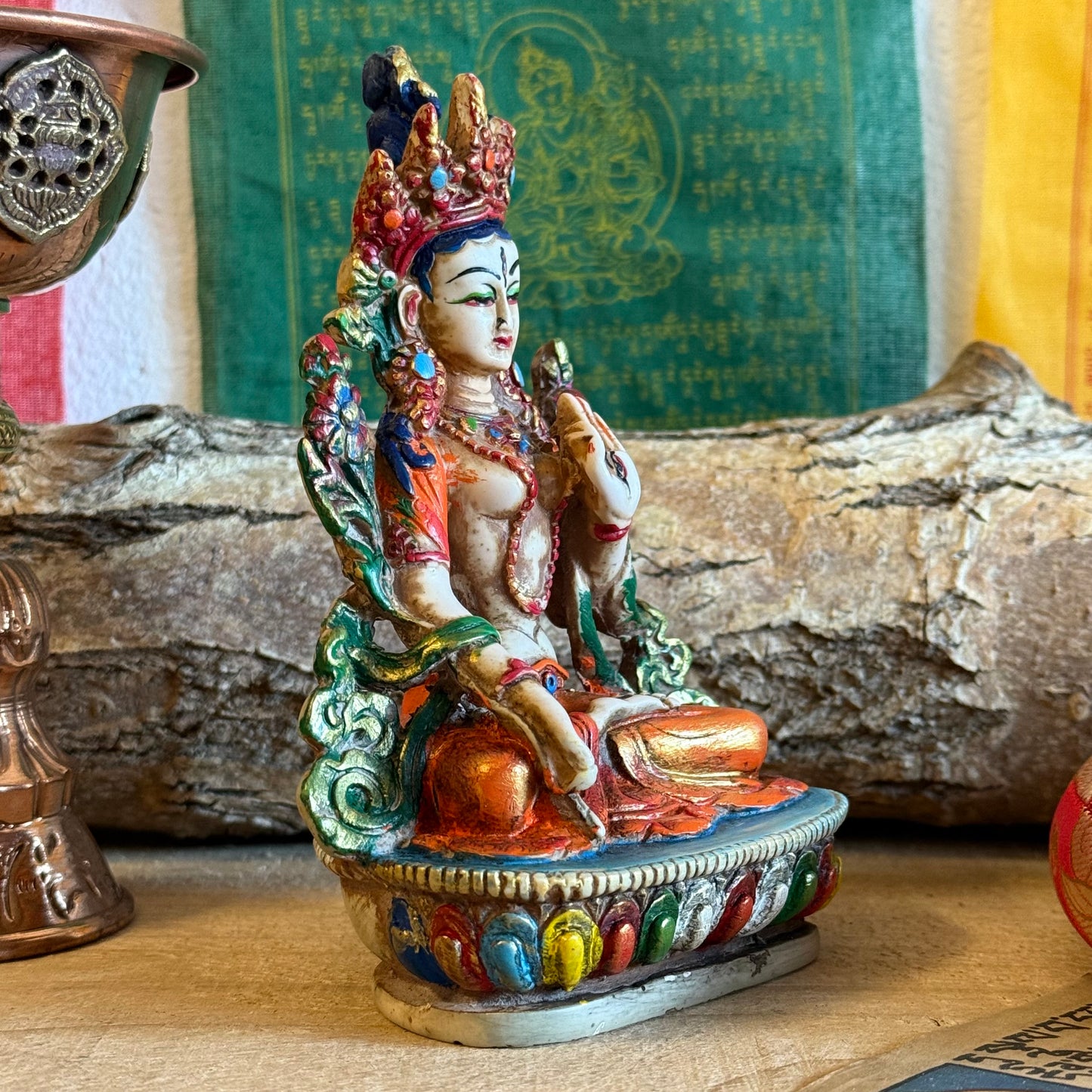 This is a beautifully intricate, handcrafted resin statue depicting White Tara, a revered goddess in Tibetan Buddhism. Known for her embodiment of compassion, healing, serenity, and longevity, she is a symbol of peace and enlightenment. The statue is skillfully painted and highlights White Tara's unique attributes:

Posture: She is seated in a tranquil, full lotus position, which signifies her meditative and composed nature, in contrast to Green Tara's more active pose with one foot extended.
Gesture: Her r