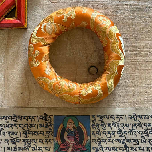 Cradle your singing bowl in divine comfort with our 11cm Doughnut Singing Bowl Cushion. As a practitioner of sound healing, I understand how every detail matters in sacred practice—including how your instruments rest when not in use.

This luxurious brocade ring isn't just a cushion; it's a ceremonial throne for your singing bowl. Designed to support smaller to medium-sized bowls, its doughnut shape stabilizes your bowl gently, allowing it to radiate its pure tones without interference. Whether you're medit