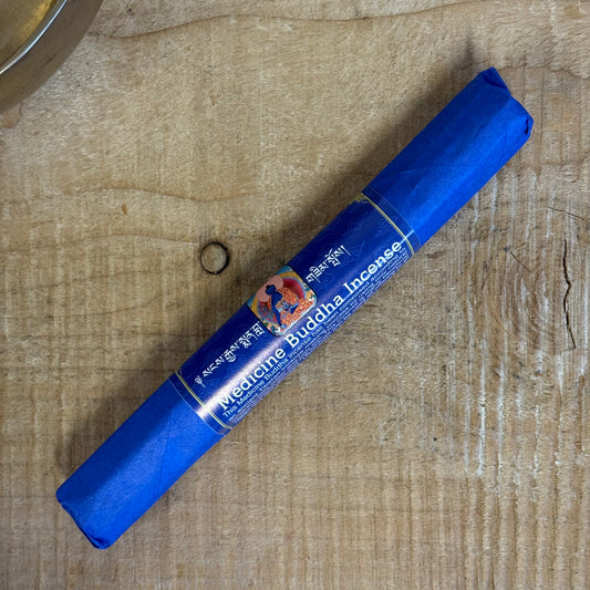 Blue cylindrical container of Medicine Buddha Incense on a wooden surface