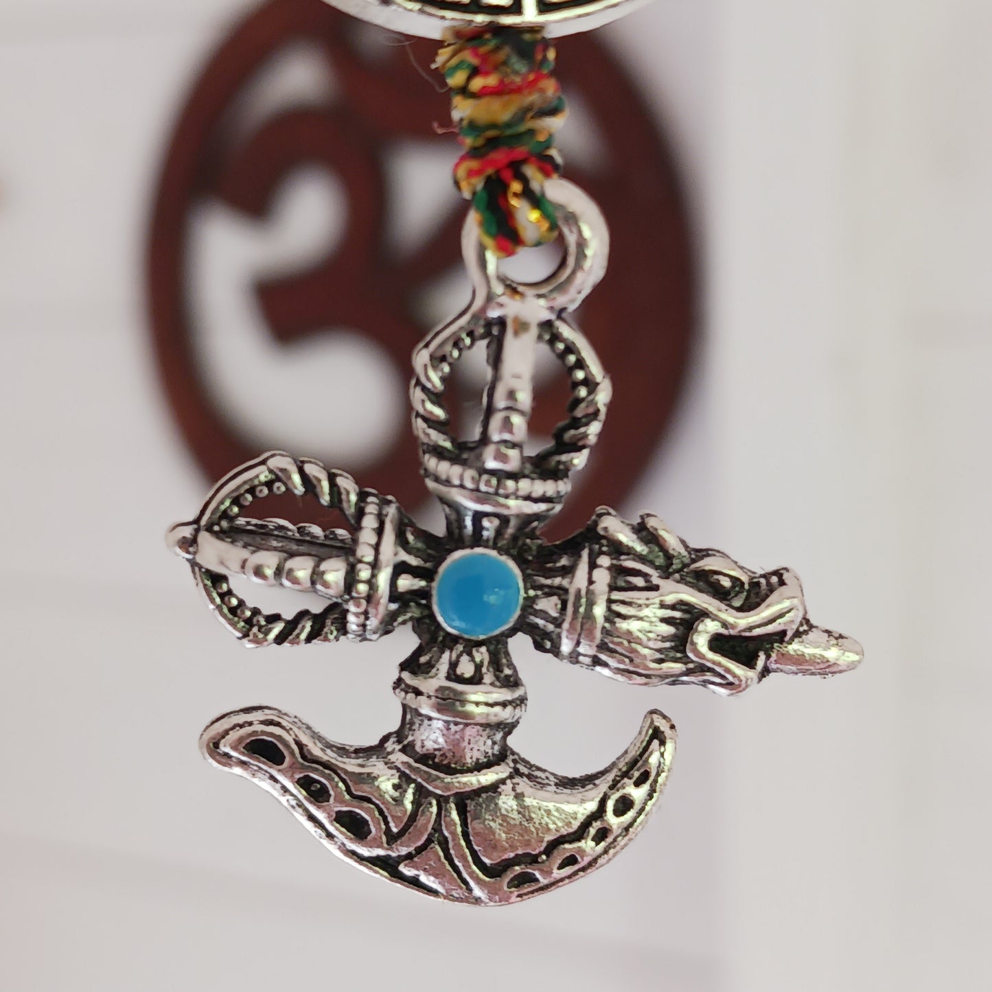 Bring the power of ancient Tibetan symbolism into your daily life with this handcrafted Buddhist protective pendant. Featuring the Double Dorje, a symbol of unwavering stability and protection from fear, and the Kartika, a ritual blade representing the cutting away of ignorance and attachment, this versatile charm can be hung in your car, placed in your home, or attached to your bag or key ring