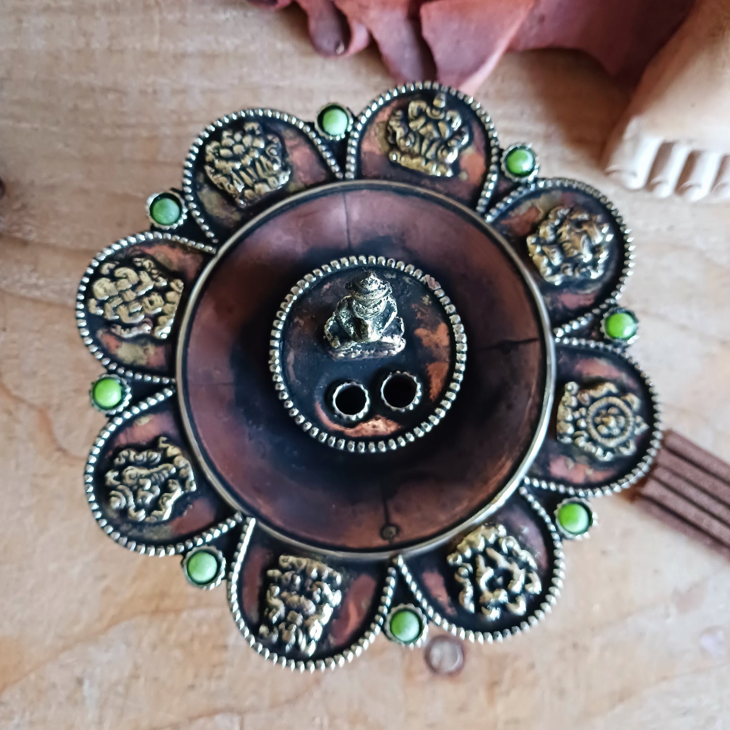 Bring harmony, tradition, and beauty into your sacred space with this handcrafted Round Copper Tibetan Incense Burner. Designed with intricate Auspicious Symbols and decorated with a Buddha and imitation green stone inlays, this burner serves both as a functional ritual tool and a stunning decorative piece.