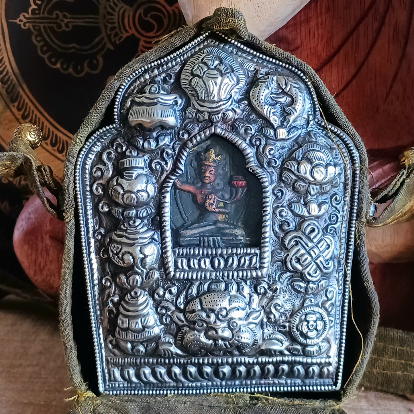 Discover the spiritual power of the Tibetan Ghau, a portable shrine and traditional prayer box used to carry sacred relics, charms, and medicinal herbs. Crafted by skilled Tibetan refugee artisans in Nepal, each Ghau serves as a portable shrine offering protection and blessings during travel. Wear it as a pendant around your neck or hang it from a waist sash or belt. This handcrafted piece is not only a spiritual talisman but also a beautiful work of art, connecting you to centuries-old Tibetan traditions.