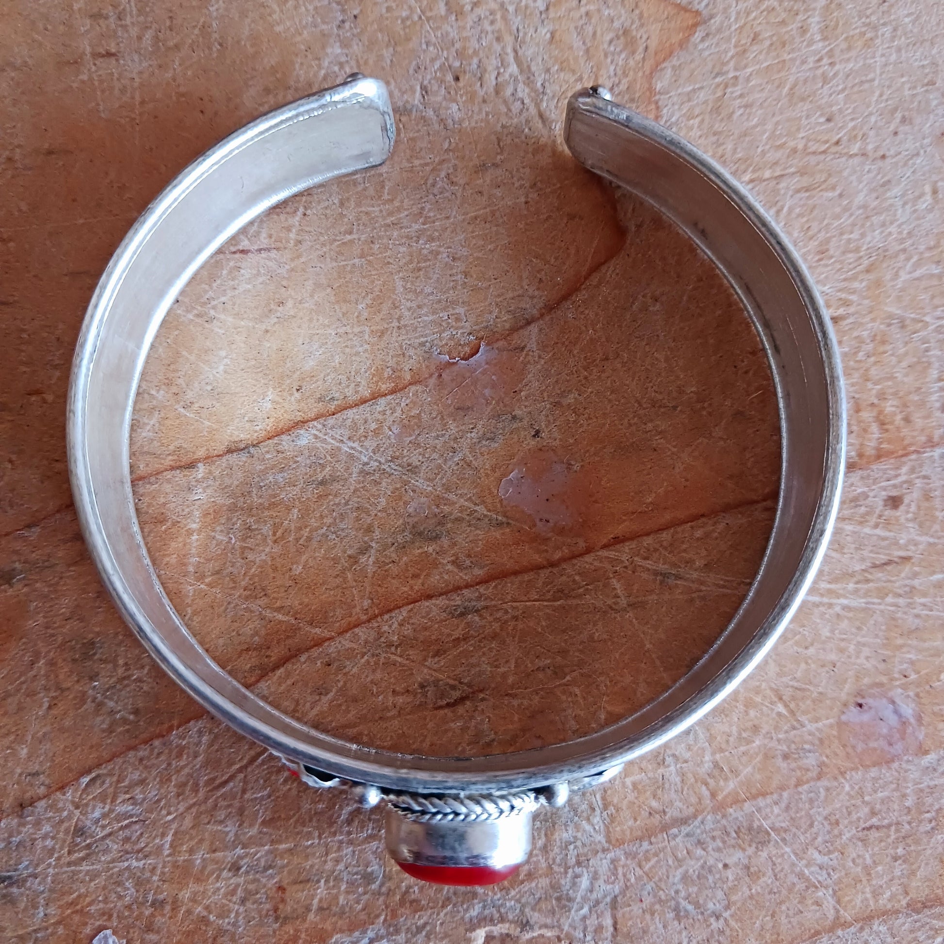 Add a touch of elegance and meaning to your jewellery collection with this handcrafted Nepalese bangle. Made from high-quality white metal, each bangle features a single coral stone, symbolizing luck and harmony, flanked by two vibrant red drop beads for a striking contrast.