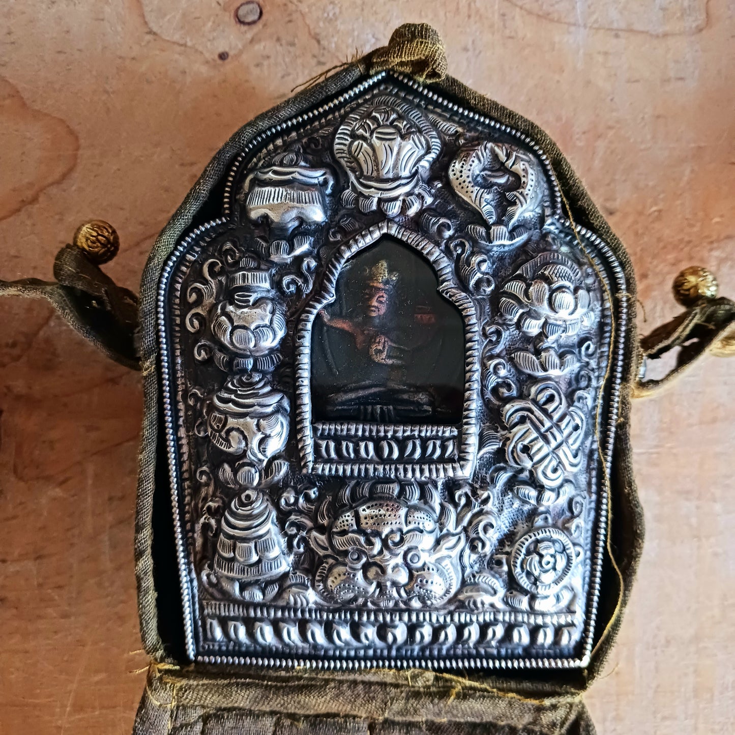 Discover the spiritual power of the Tibetan Ghau, a portable shrine and traditional prayer box used to carry sacred relics, charms, and medicinal herbs. Crafted by skilled Tibetan refugee artisans in Nepal, each Ghau serves as a portable shrine offering protection and blessings during travel. Wear it as a pendant around your neck or hang it from a waist sash or belt. This handcrafted piece is not only a spiritual talisman but also a beautiful work of art, connecting you to centuries-old Tibetan traditions.