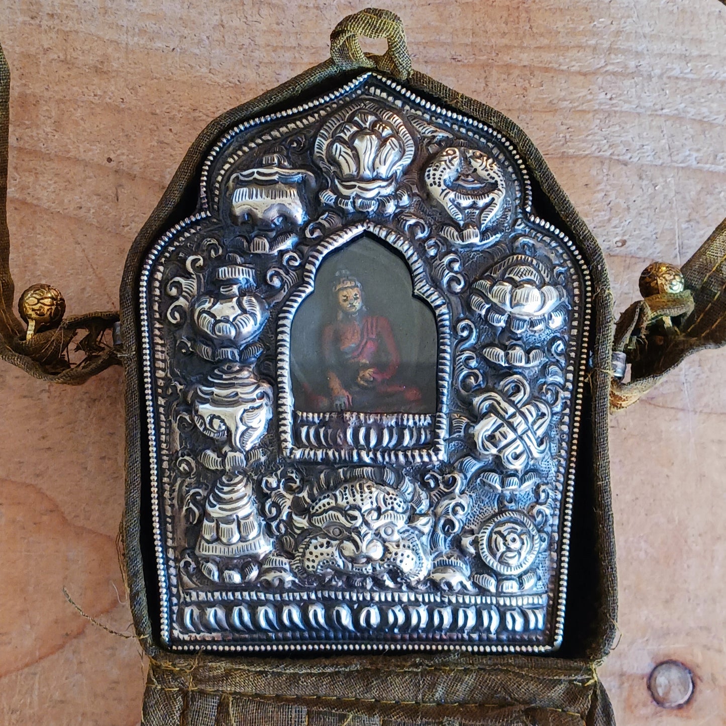 Discover the spiritual power of the Tibetan Ghau, a portable shrine and traditional prayer box used to carry sacred relics, charms, and medicinal herbs. Crafted by skilled Tibetan refugee artisans in Nepal, each Ghau serves as a portable shrine offering protection and blessings during travel. Wear it as a pendant around your neck or hang it from a waist sash or belt. This handcrafted piece is not only a spiritual talisman but also a beautiful work of art, connecting you to centuries-old Tibetan traditions.