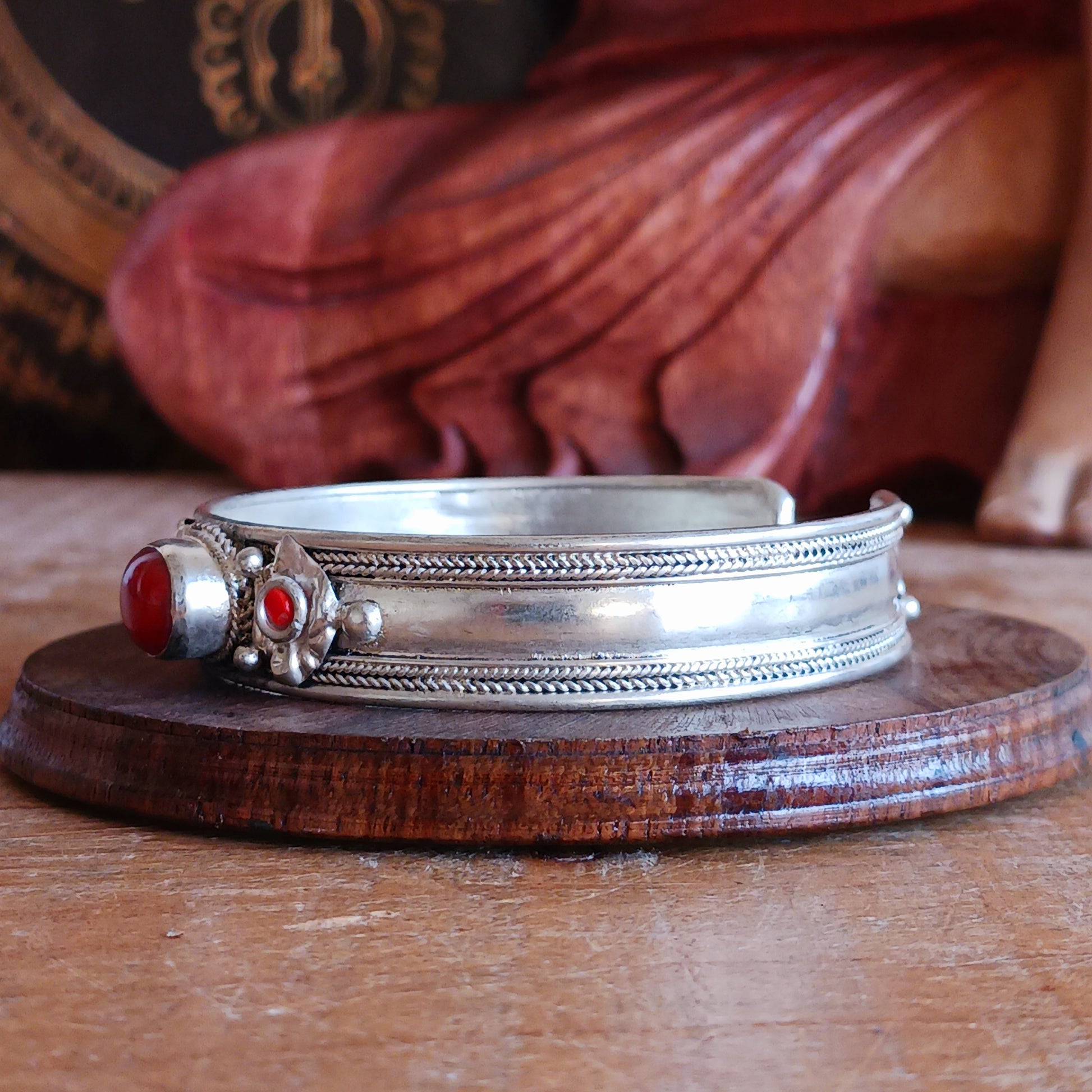 Add a touch of elegance and meaning to your jewellery collection with this handcrafted Nepalese bangle. Made from high-quality white metal, each bangle features a single coral stone, symbolizing luck and harmony, flanked by two vibrant red drop beads for a striking contrast.