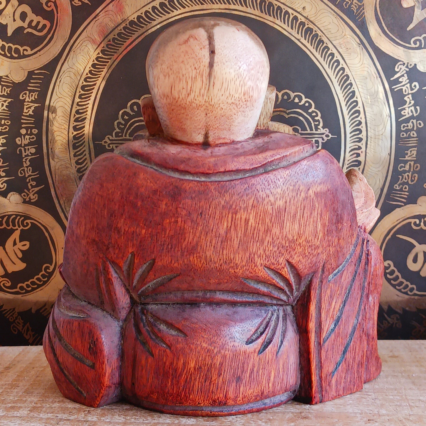 This charming Hand Carved Laughing Buddha is seated in a relaxed pose with a broad, joyful grin and rounded belly, beautifully carved from warm two-tone wood. The natural wood grain is enhanced with a protective varnish, highlighting the intricate details of his robes, prayer beads and expressive face.