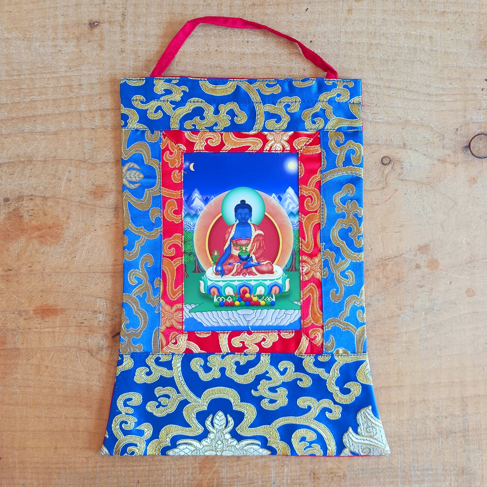 Bring healing energy, restoration, and spiritual harmony into your home with this beautiful Medicine Buddha Traditional Printed Thangka, elegantly presented in a handmade brocade frame.