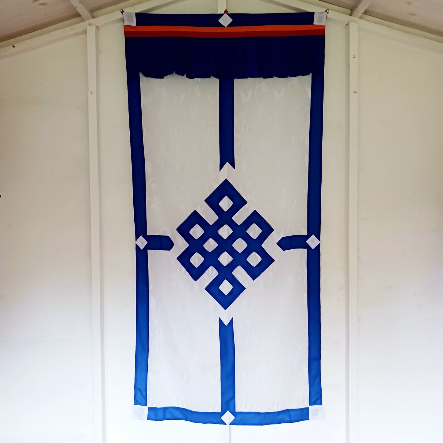 Bring spiritual harmony and traditional Himalayan craftsmanship into your home with this handmade Tibetan Buddhist Endless Knot Door Curtain. Crafted in a white fabric, this semi-transparent curtain allows natural light to pass through, creating a warm and calming atmosphere.
